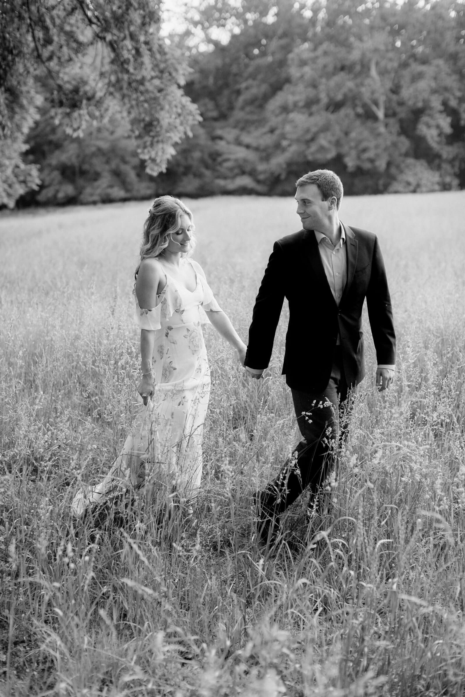 Groom leading bride through a field while holding hands at an engagement session at Tuckahoe Plantation