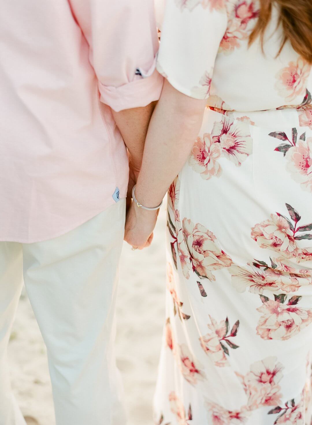 couple at engagement session on the beach holding hands together