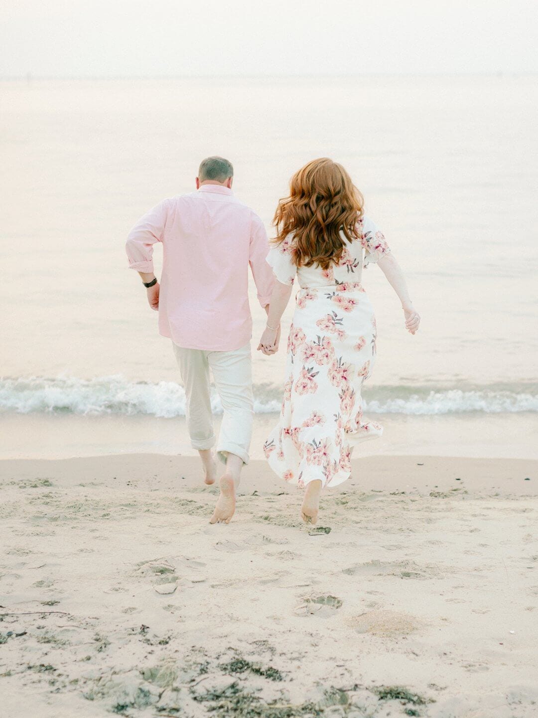 couple at engagement session on the beach running into the water together