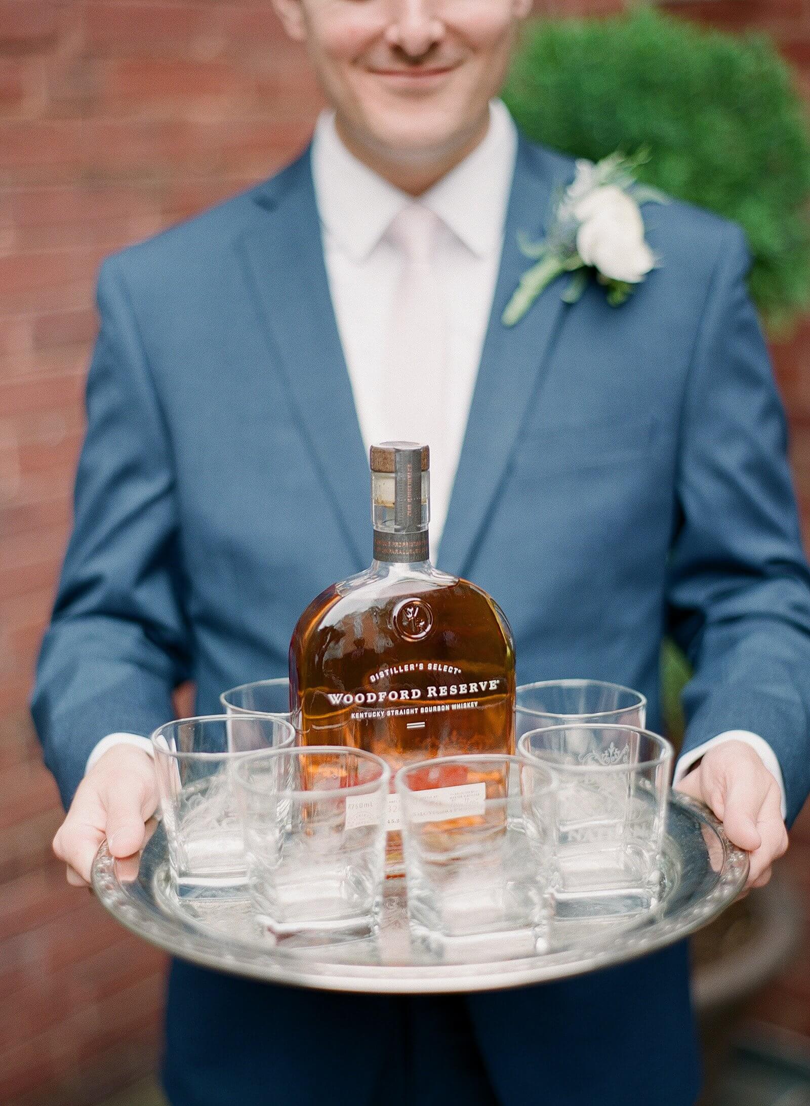 Groom with silver tray of bourbon