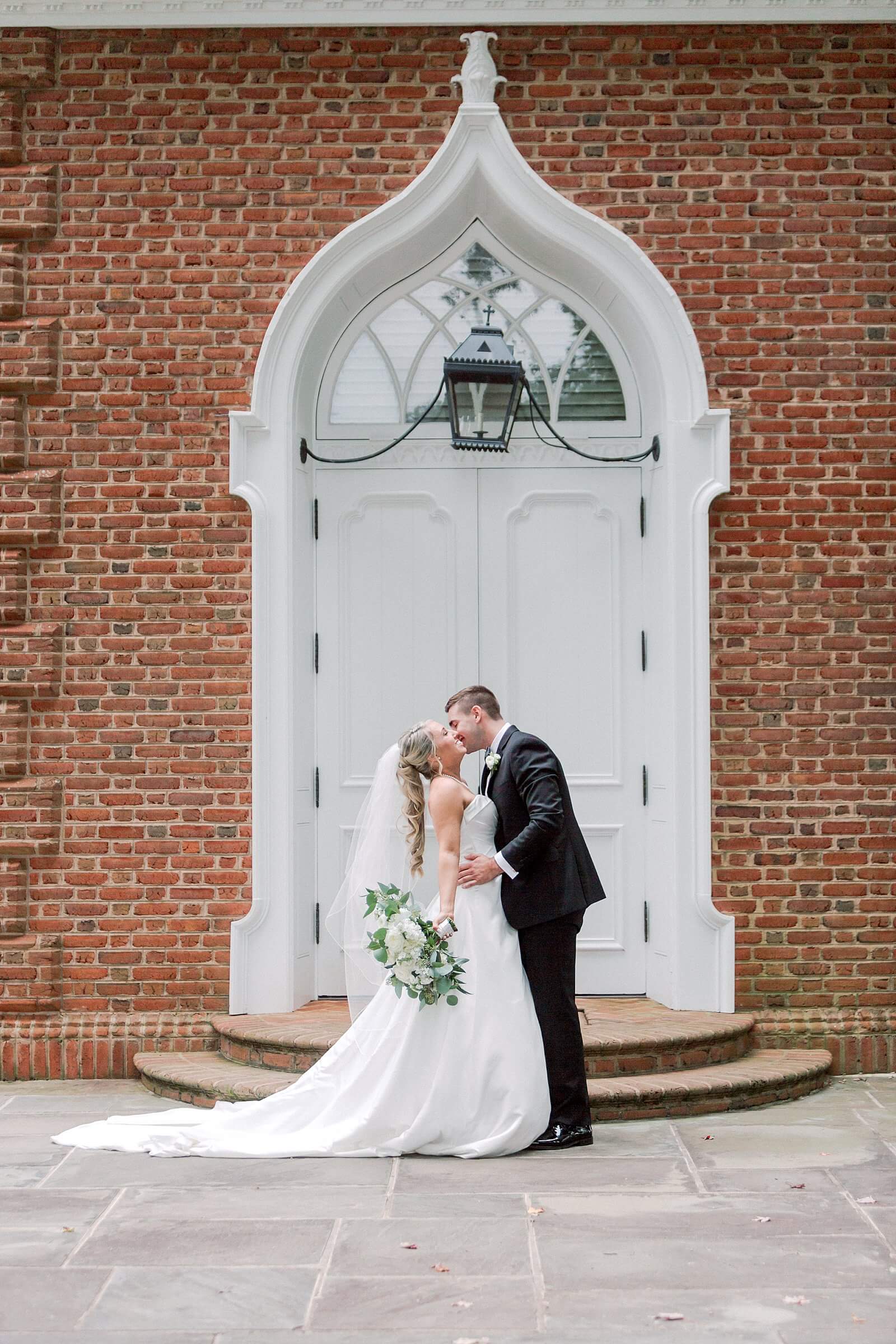 Bride and groom embrace outside of small chapel at Trump Winery