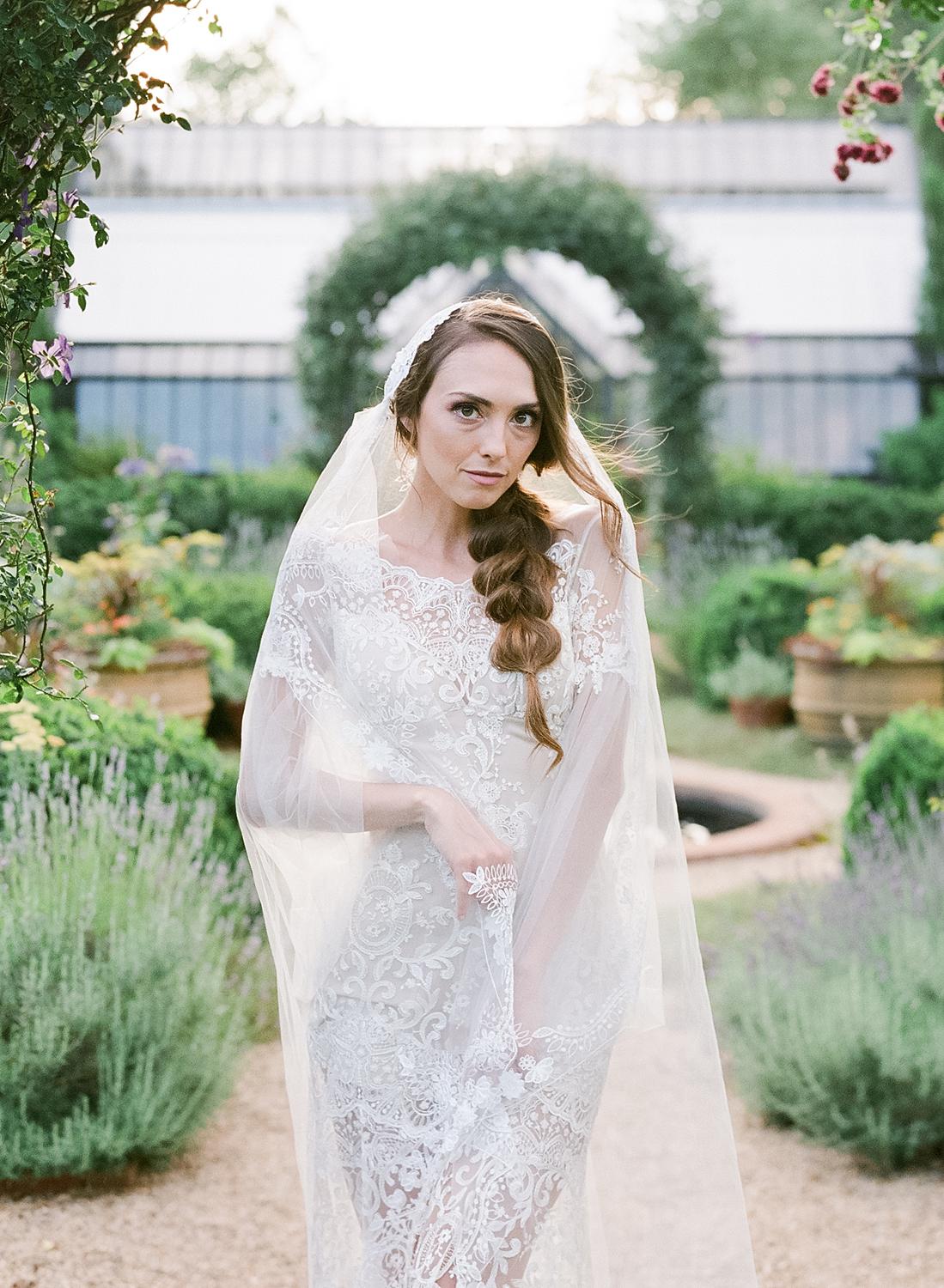 Bride in designer Claire Pettibone Gown holding her veil at Waterperry Farm Wedding