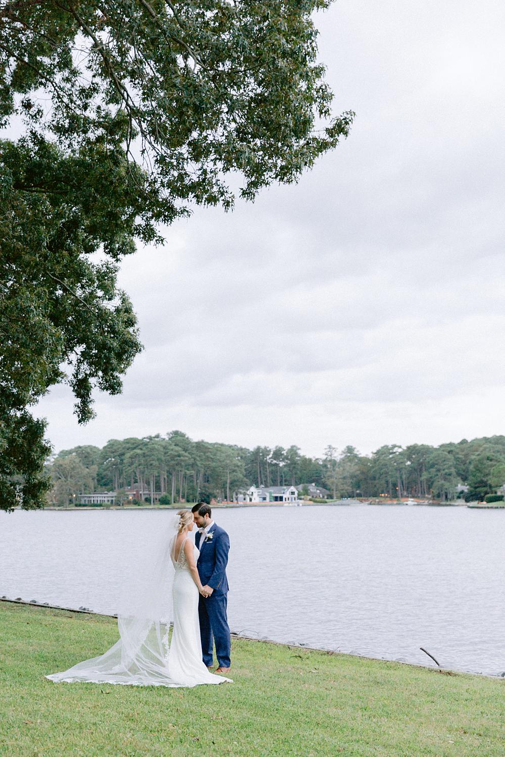Bride and groom kissing by the water after their intimate home wedding