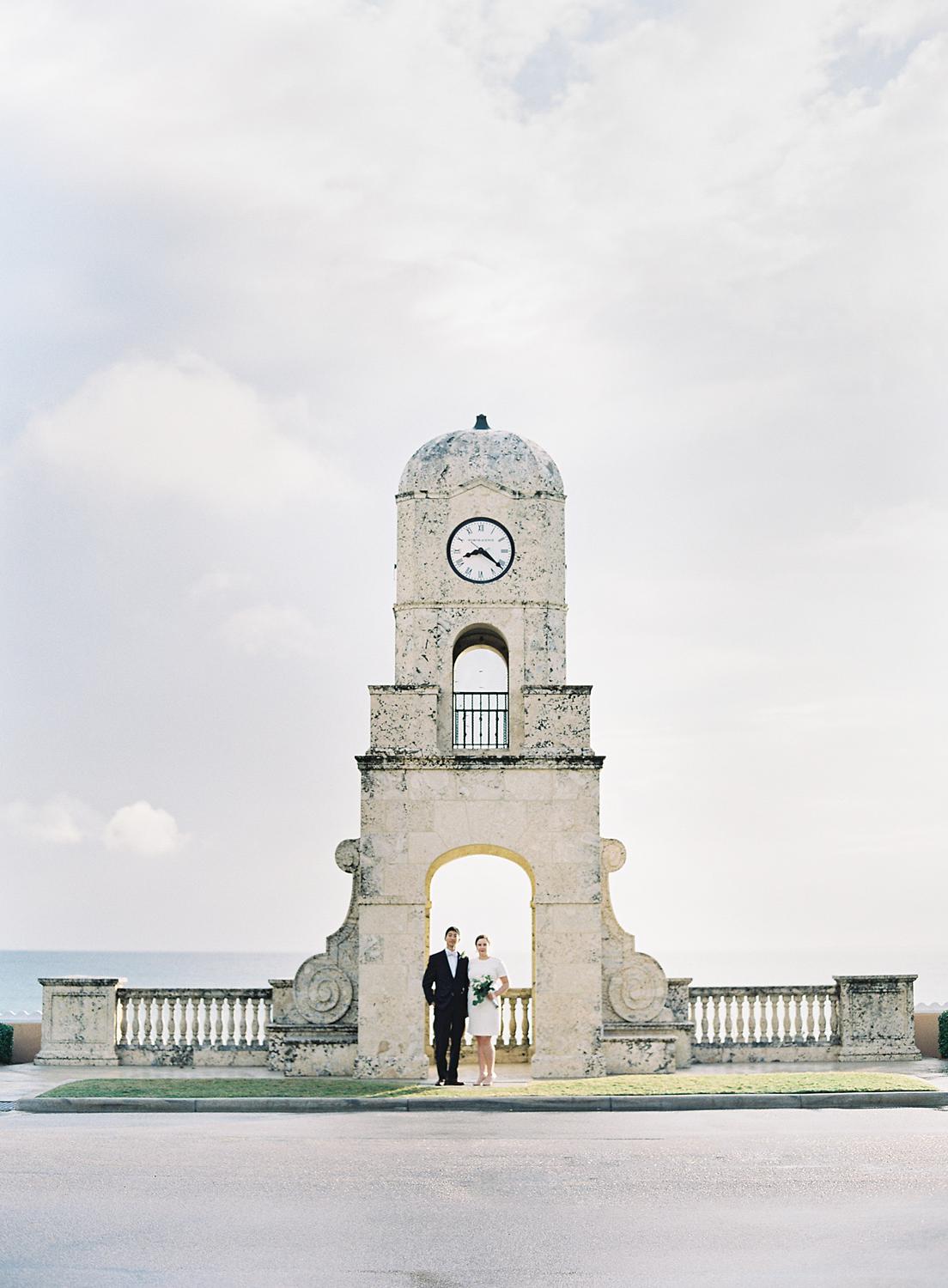Bride and groom standing under Worth Avenue Clock Tower
