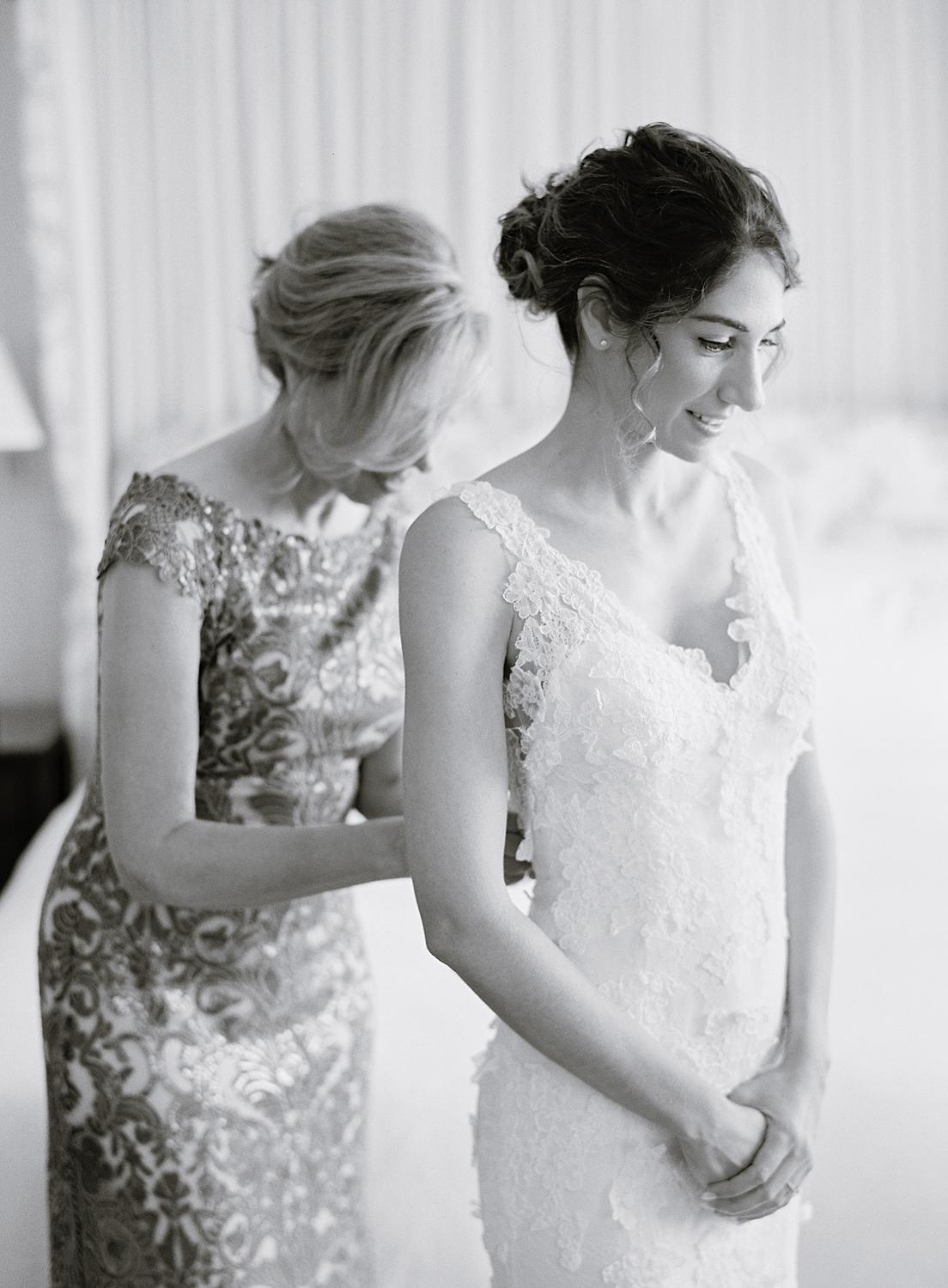 Bride getting buttoned into her wedding gown by her mother for her DAR Constitution Hall Wedding.