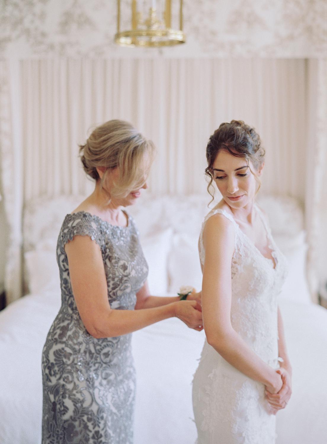 Bride getting buttoned into her wedding gown by her mother for her DAR Constitution Hall Wedding.