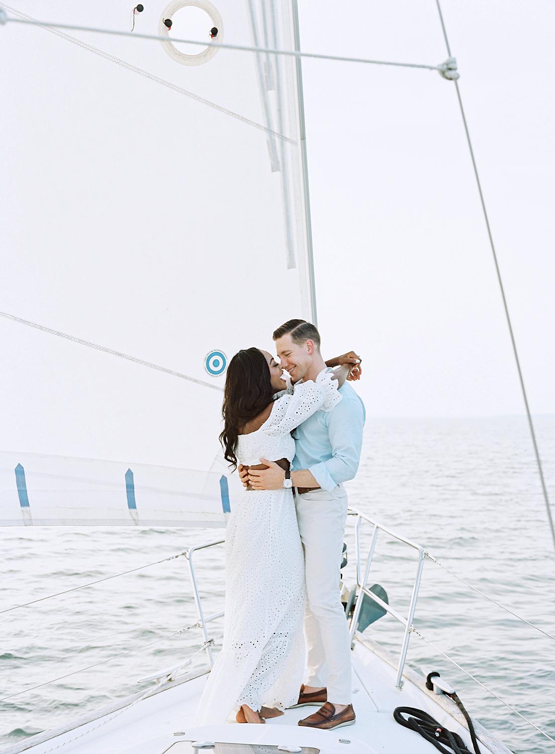 Bride throwing her arms around groom on the boat on The Chesapeake bay.