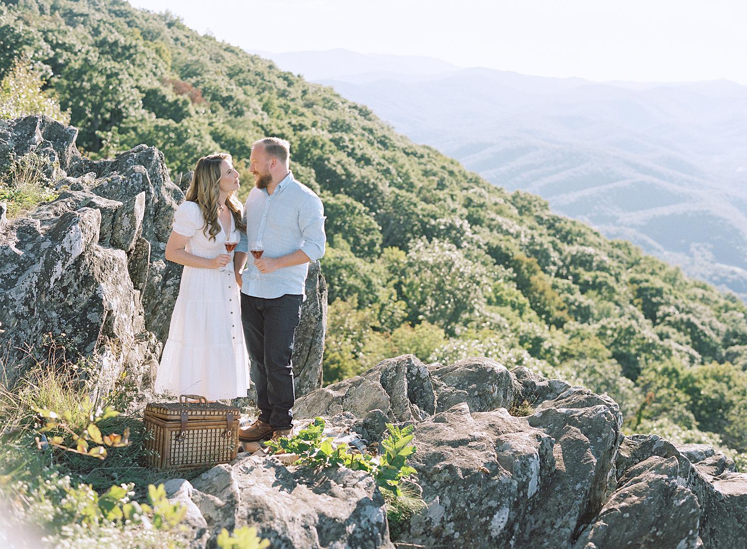 Bride and groom kissing and enjoying some wine together during their Blue Ridge Mountains engagement session at Ravens Roost.