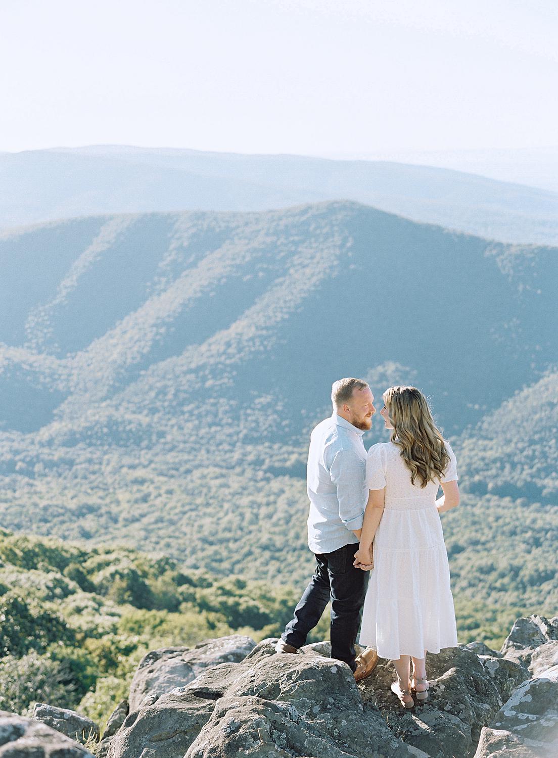 Bride and groom holding hands and looking over the valley from atop The Blue Ridge Mountains.