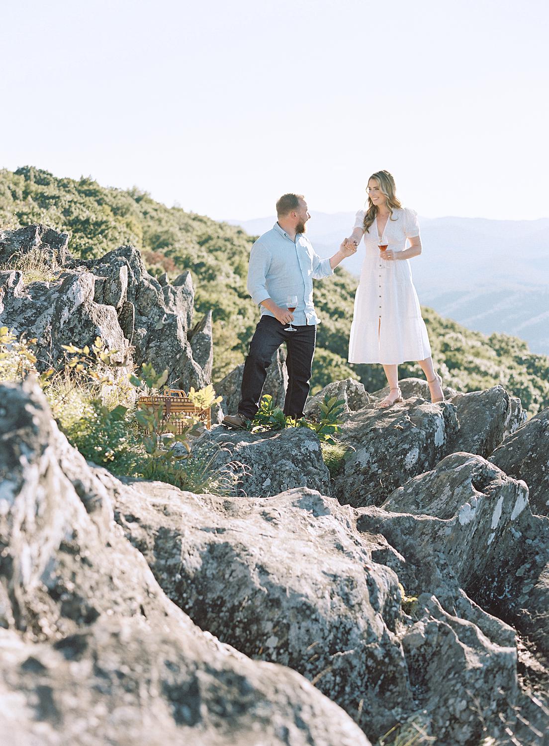 Bride and groom walking over rocks during their Blue Ridge Mountains engagement session at Ravens Roost.