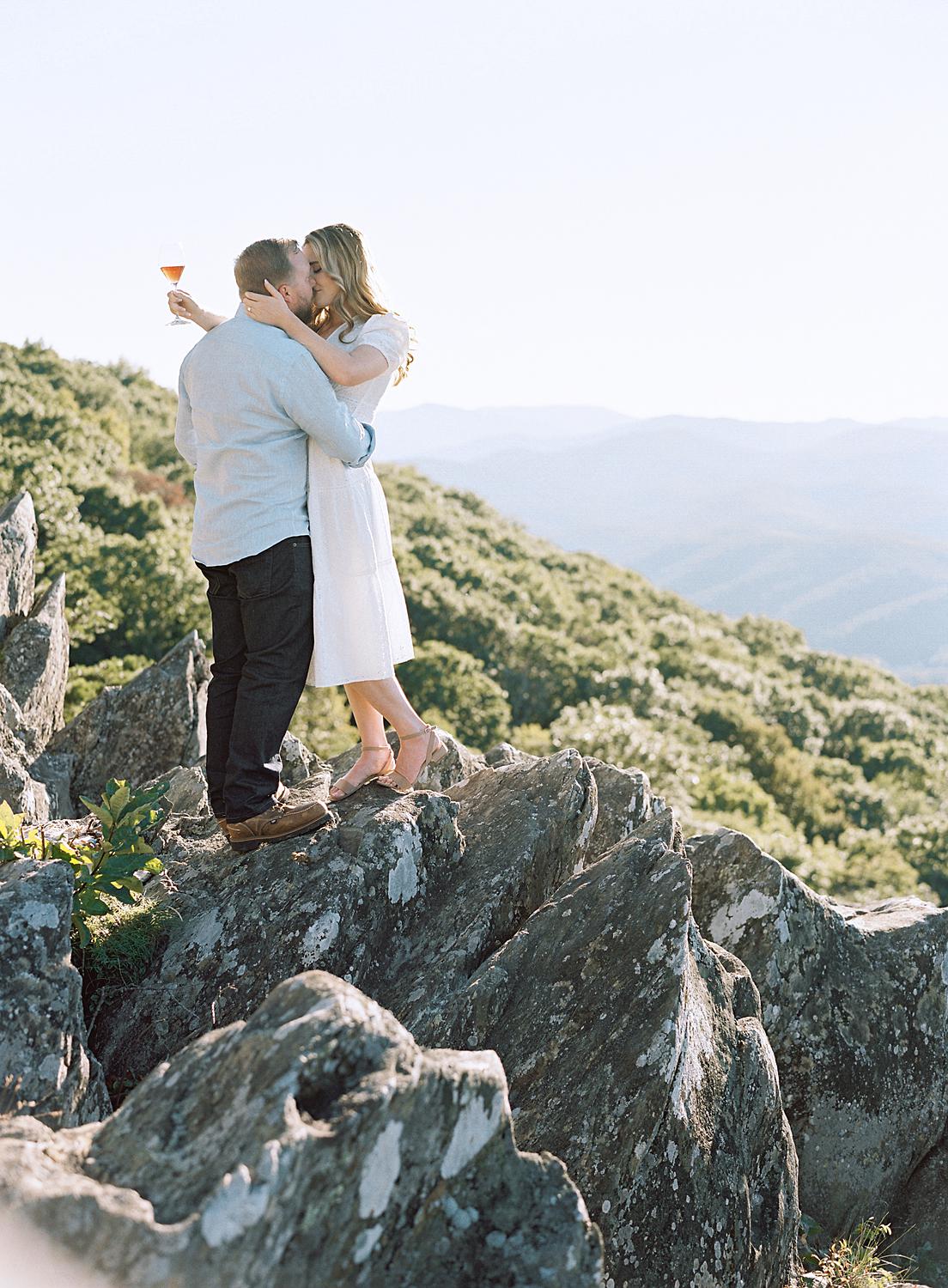 Bride and groom kissing on the rocks during their Blue Ridge Mountains Engagement session at Ravens Roost.