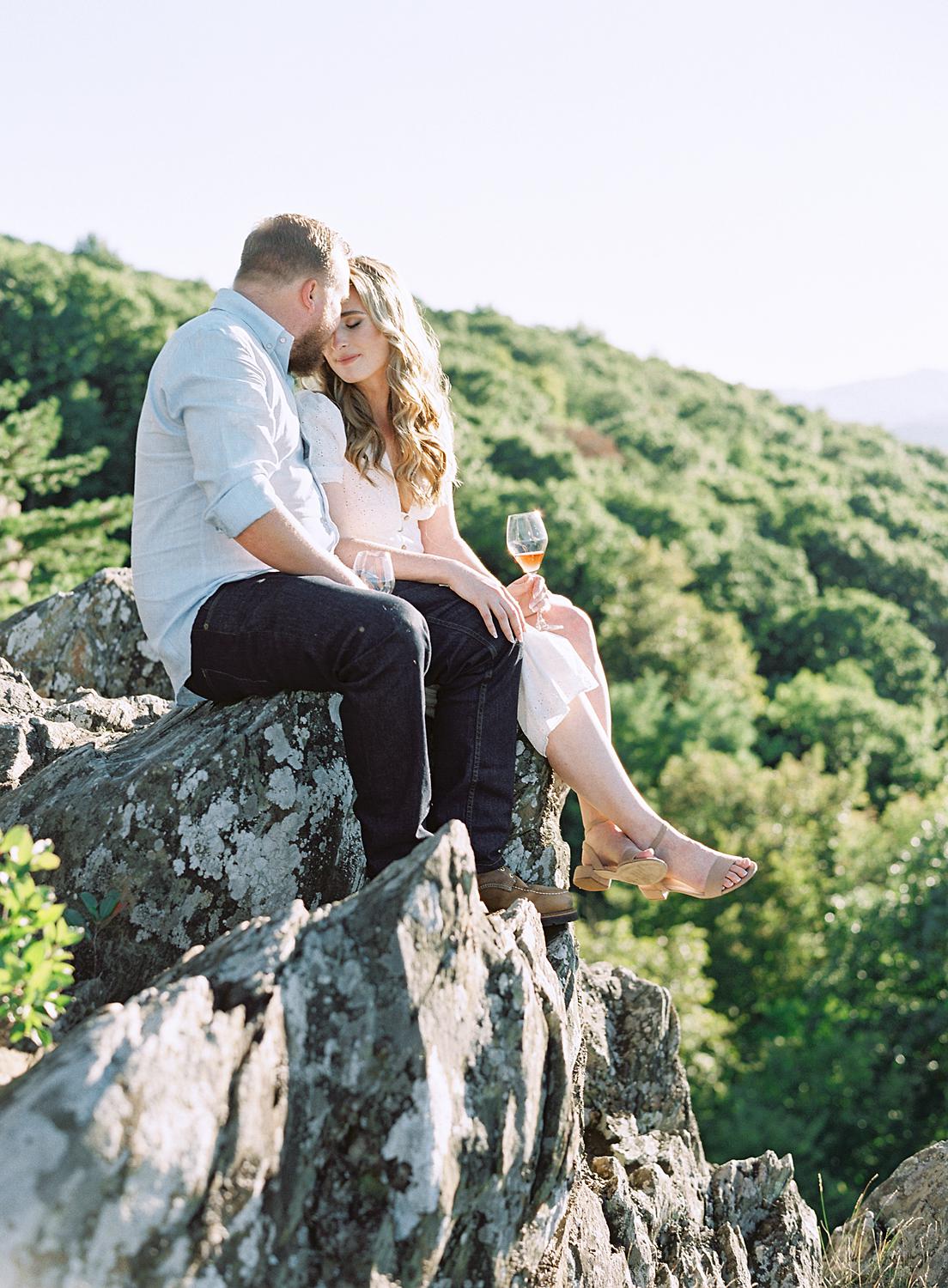 Bride and groom sitting on the rocks during their Blue Ridge Mountains Engagement session at Ravens Roost.