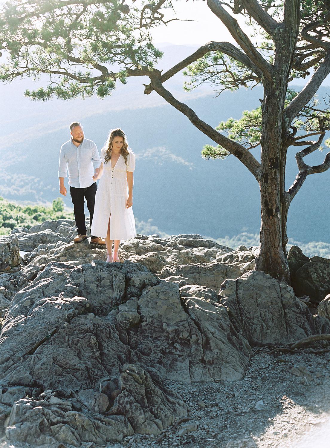 Bride and groom walking over rocks atop Ravens Roost during their Blue Ridge Mountains engagement session.