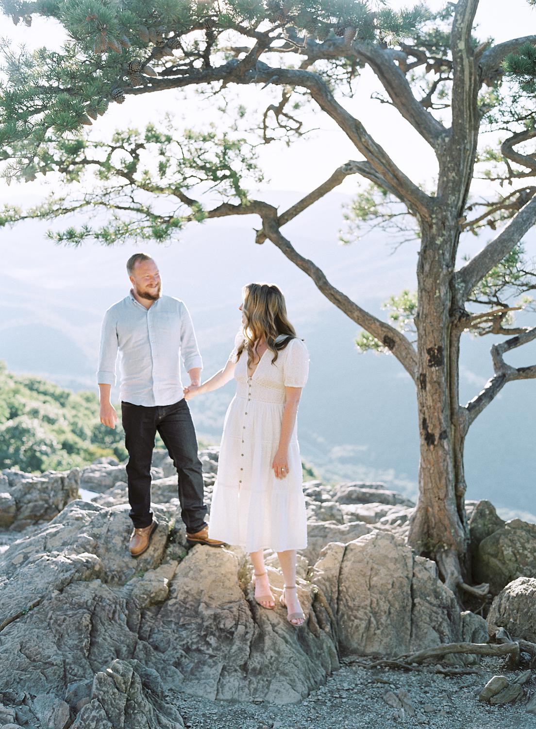Bride and groom walking over rocks atop Ravens Roost during their Blue Ridge Mountains engagement session.