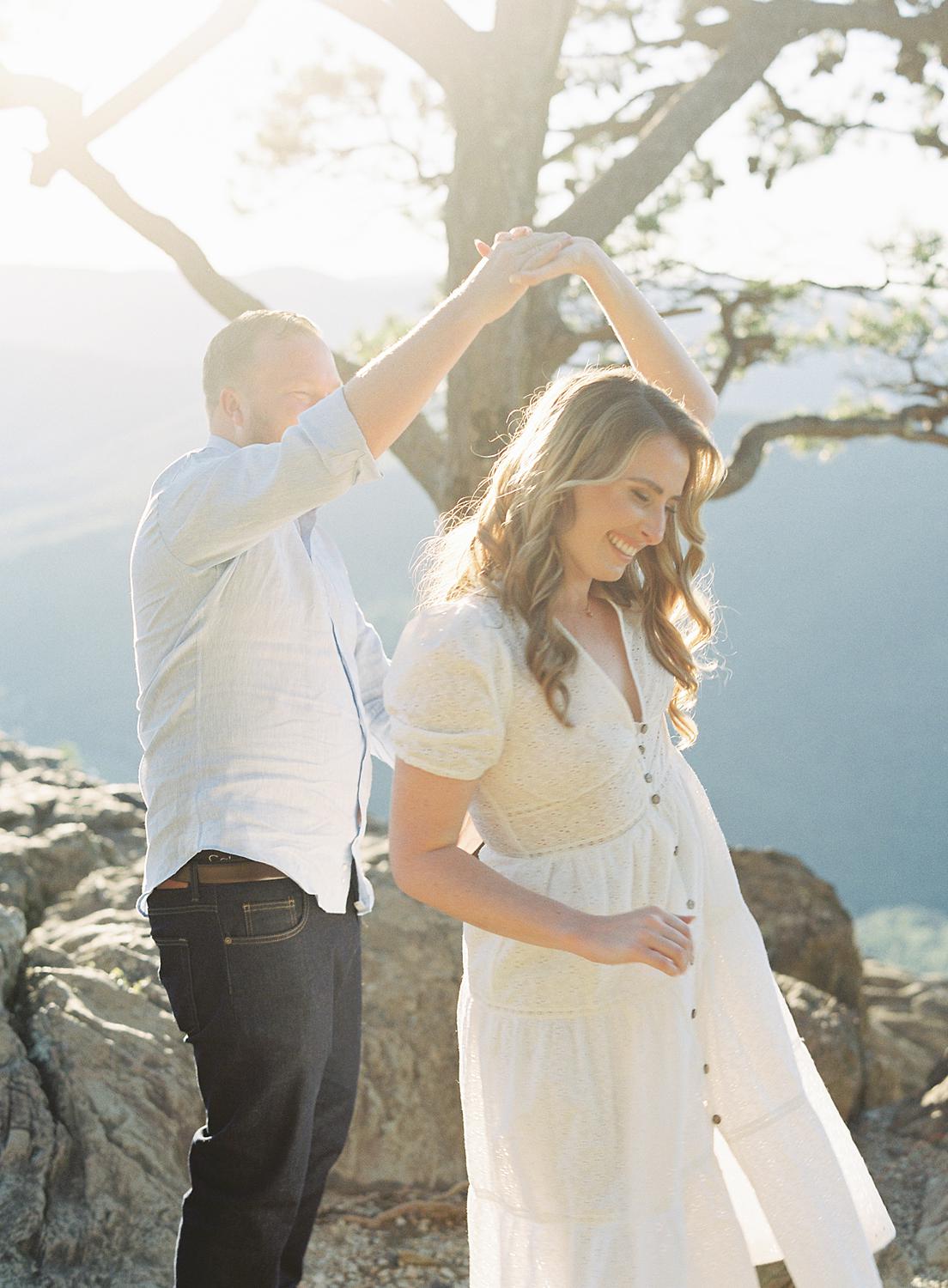 Groom twirling bride atop Ravens Roost during their Blue Ridge Mountains engagement session.