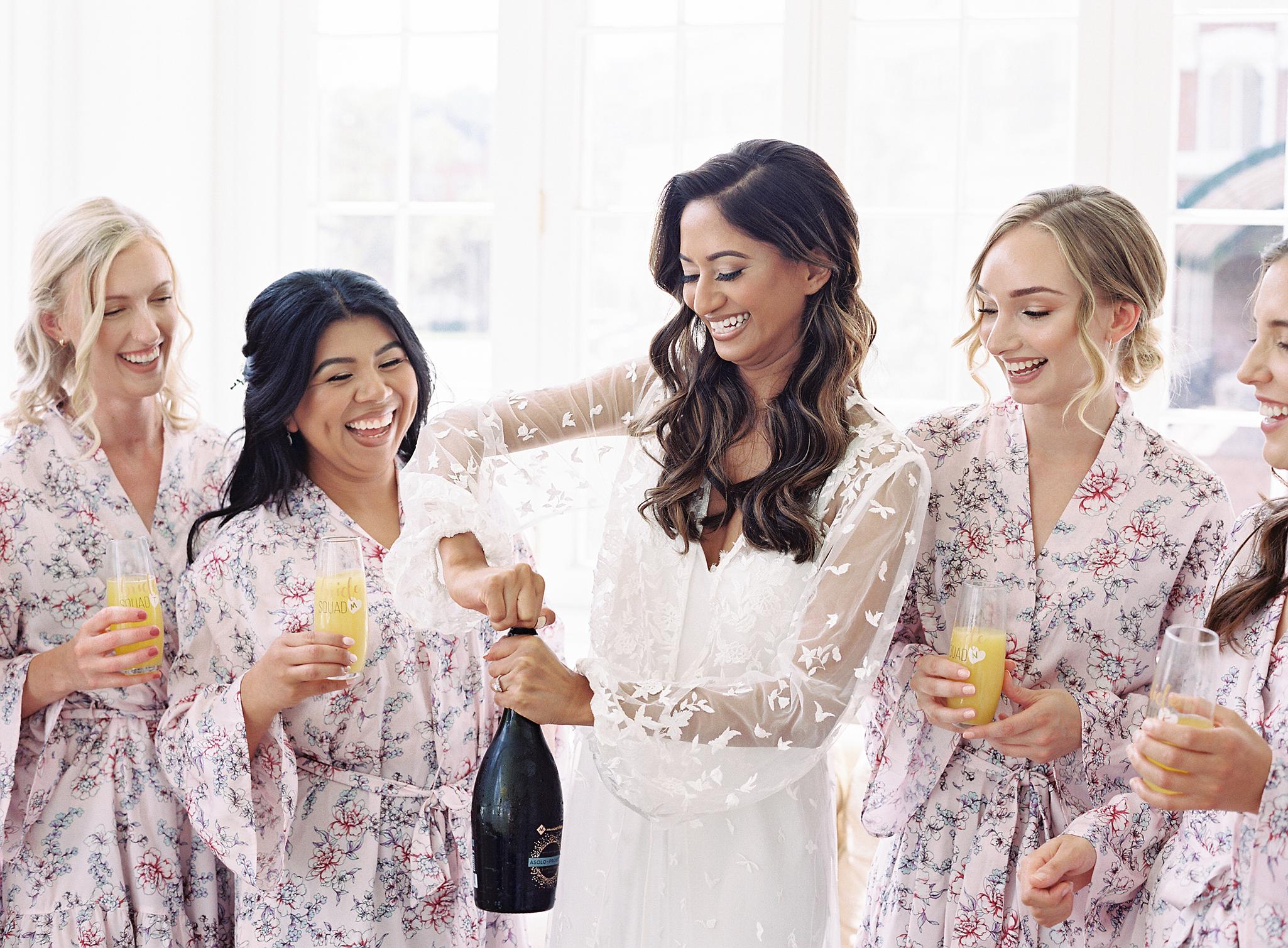 Bride opening champagne in her wedding robe before getting into her wedding dress.