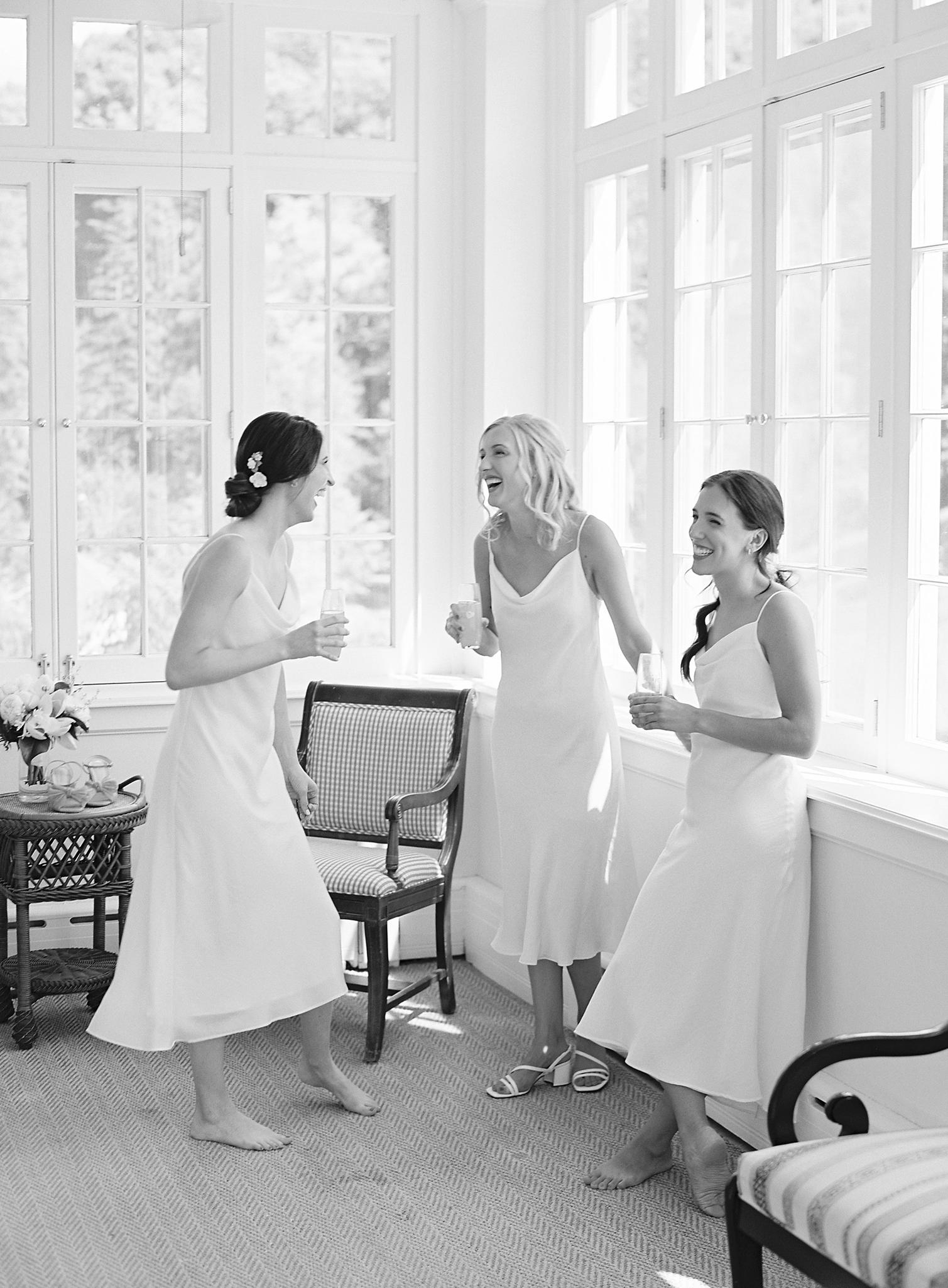 Bridesmaids laughing together in their white bridesmaids dresses before the Omni Homestead Wedding.