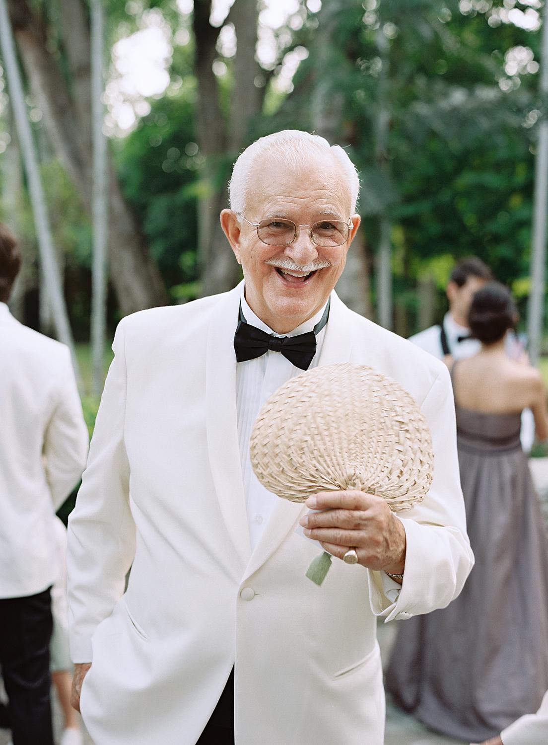 Older gentleman in white dinner jacket fans himself before ceremony at Altos de Chavón.