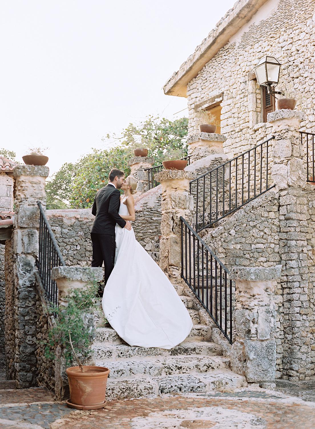 Bride and groom kiss on stone steps during their Altos de Chavón wedding.
