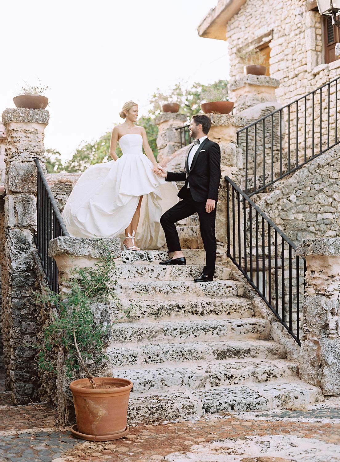 Bride and groom walk down stone staircase at Altos de Chavón wedding.