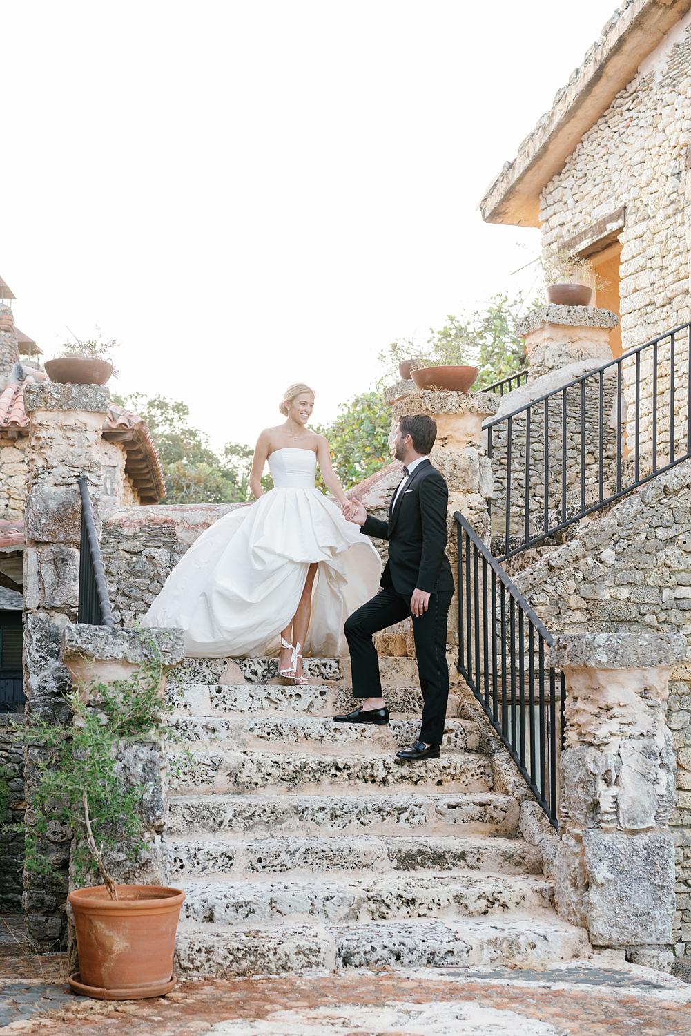 Bride and groom walk down stone staircase at Altos de Chavón wedding.