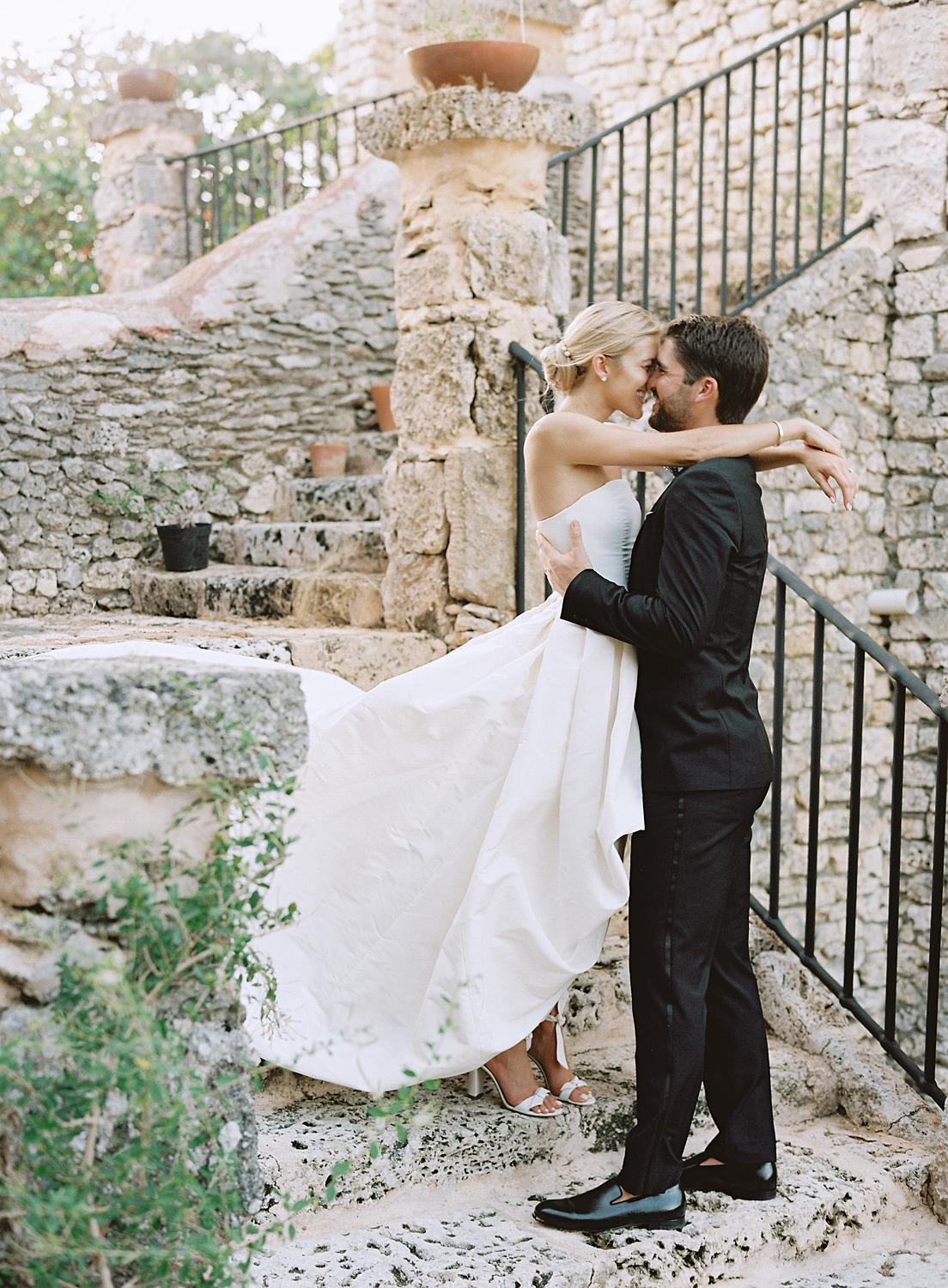 Bride and groom embrace on stone staircase at their Altos de Chavón wedding.