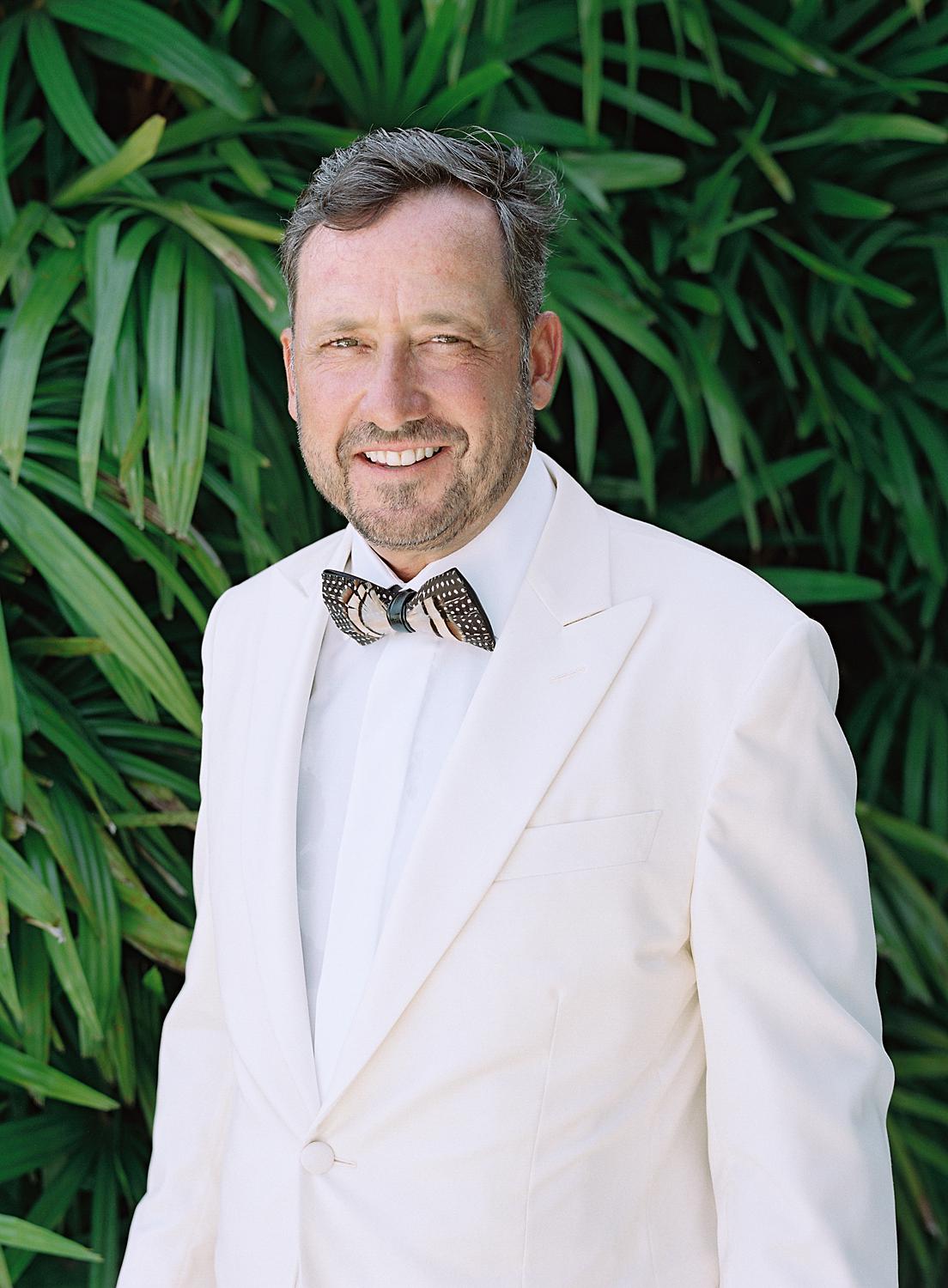 Portrait of the father of the bride in white dinner jacket against the greenery of Altos de Chavón.