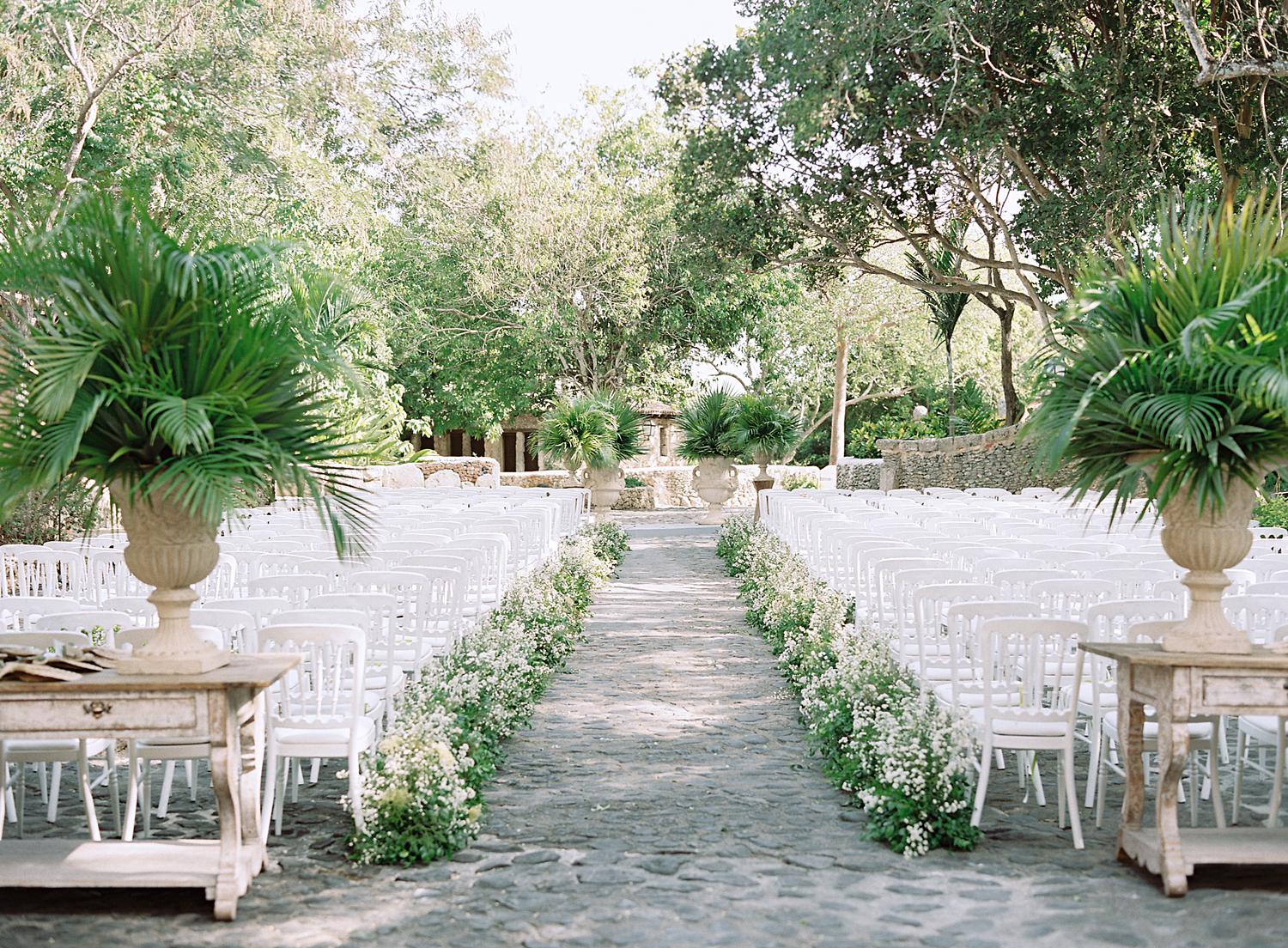 Ceremony details with a greenery lined aisle for an outdoor wedding at Altos de Chavón.