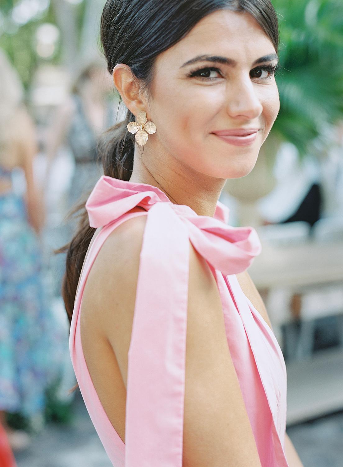 Image of glamorous guest wearing a dress with pink shoulder bows at an Altos de Chavón wedding.