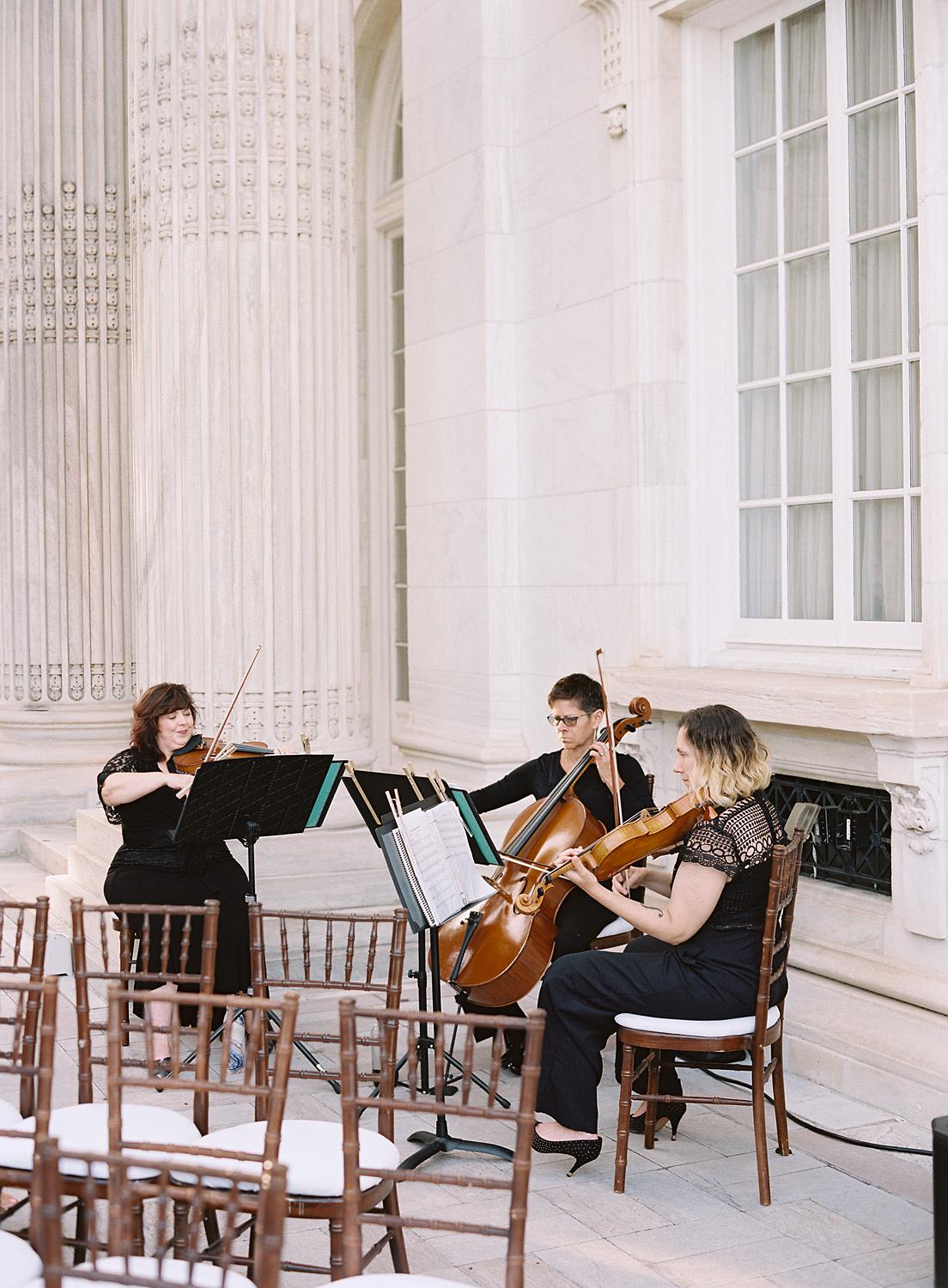 A group of three string musicians playing for a DAR Constitution Hall wedding.