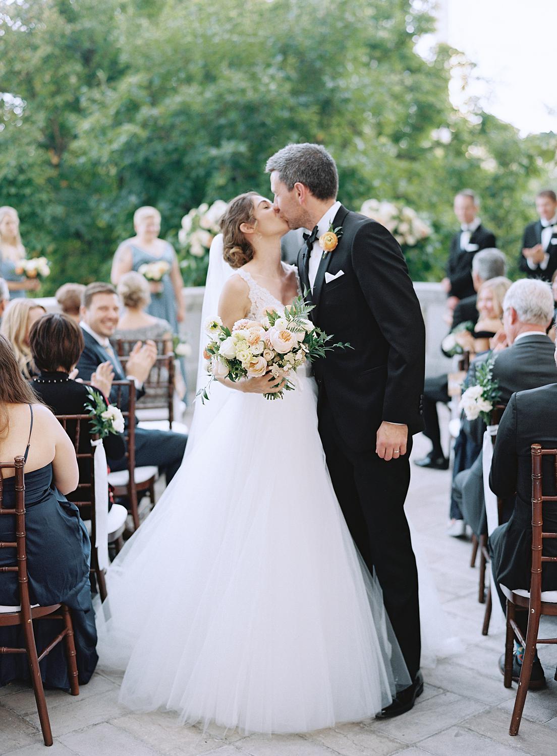 Bride and groom kissing as they walk back down the aisle after their ceremony at DAR Constitutional Hall.