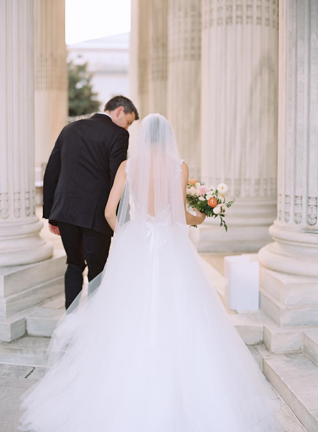 Bride and groom stepping into the columns of DAR Constitution Hall after their ceremony.