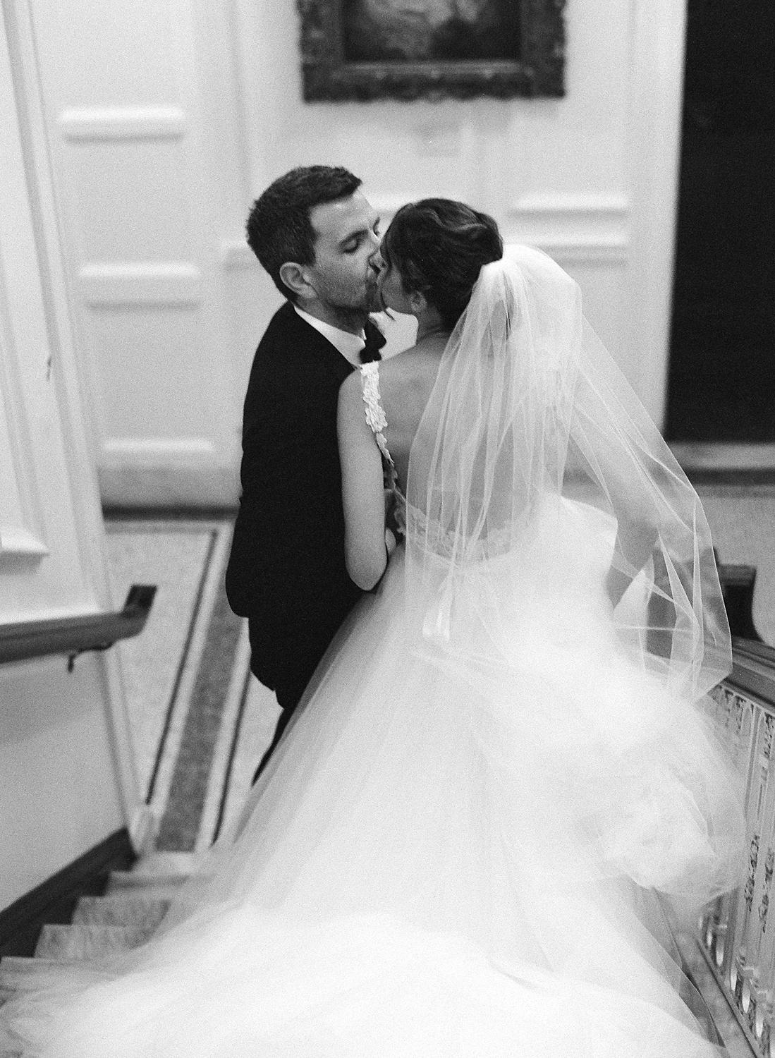 Bride and groom walking down the stairs and kissing at their DAR Constitution Hall wedding.