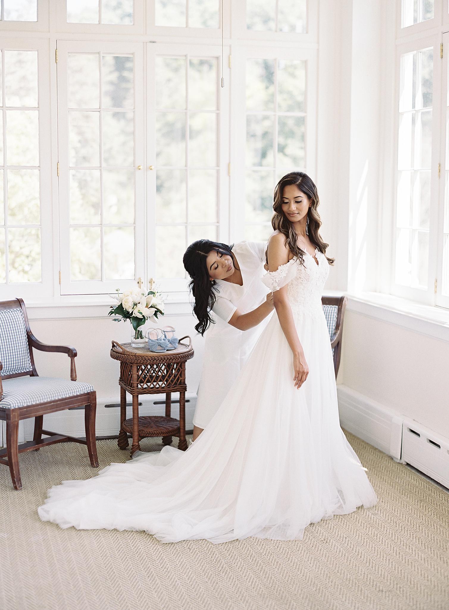 Bride getting buttoned up into here dress by sister for here Omni Homestead Resort Wedding.