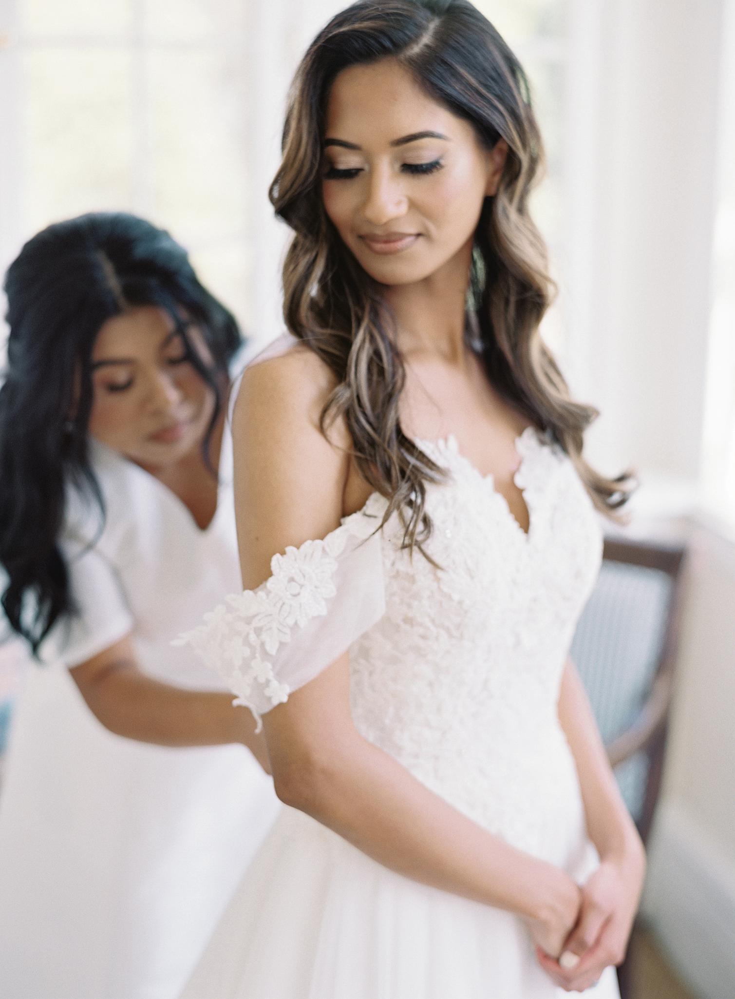 Bride getting buttoned up into here dress by sister for here Omni Homestead Resort Wedding.