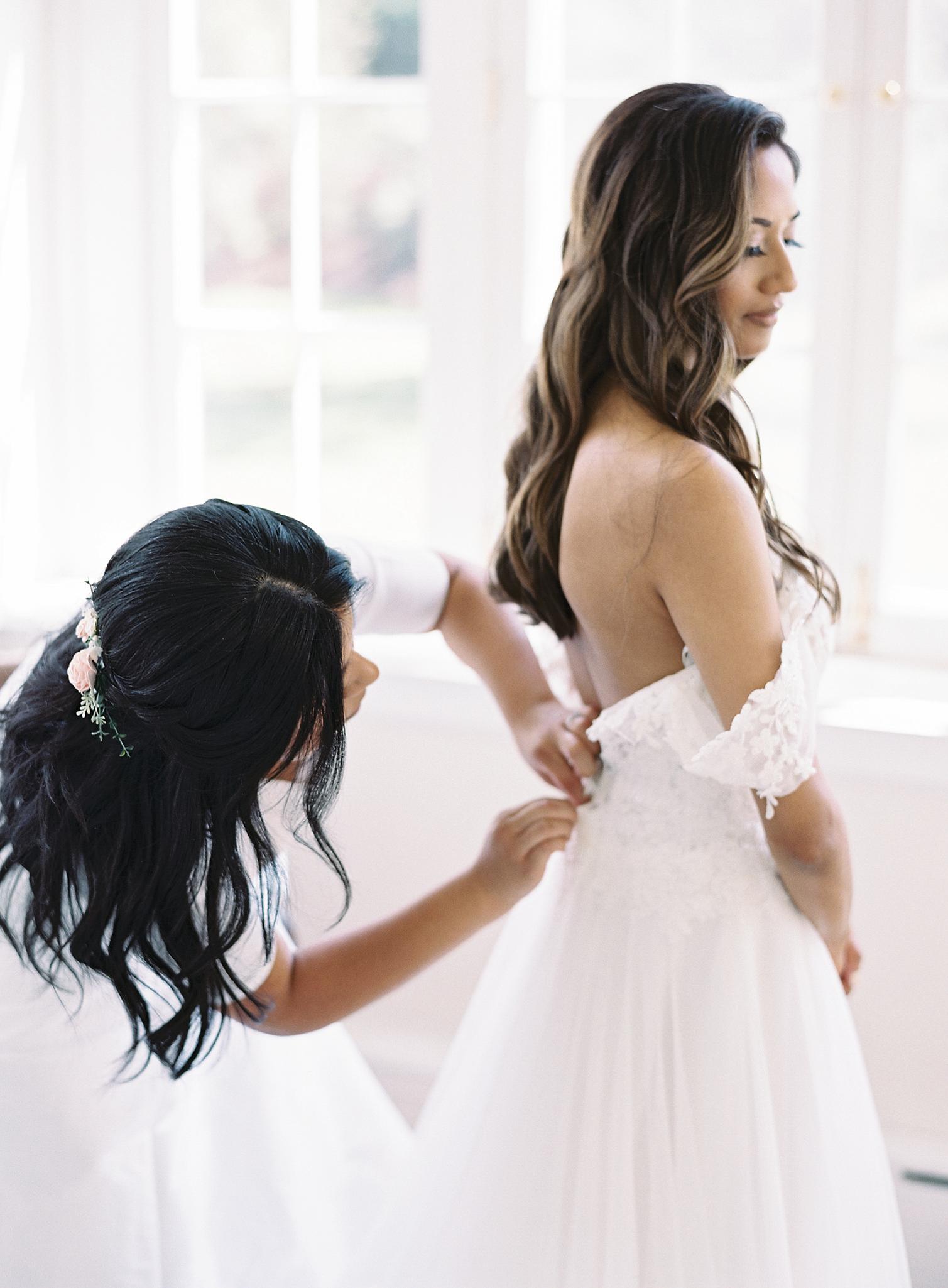 Bride getting buttoned up into here dress by sister for here Omni Homestead Resort Wedding.