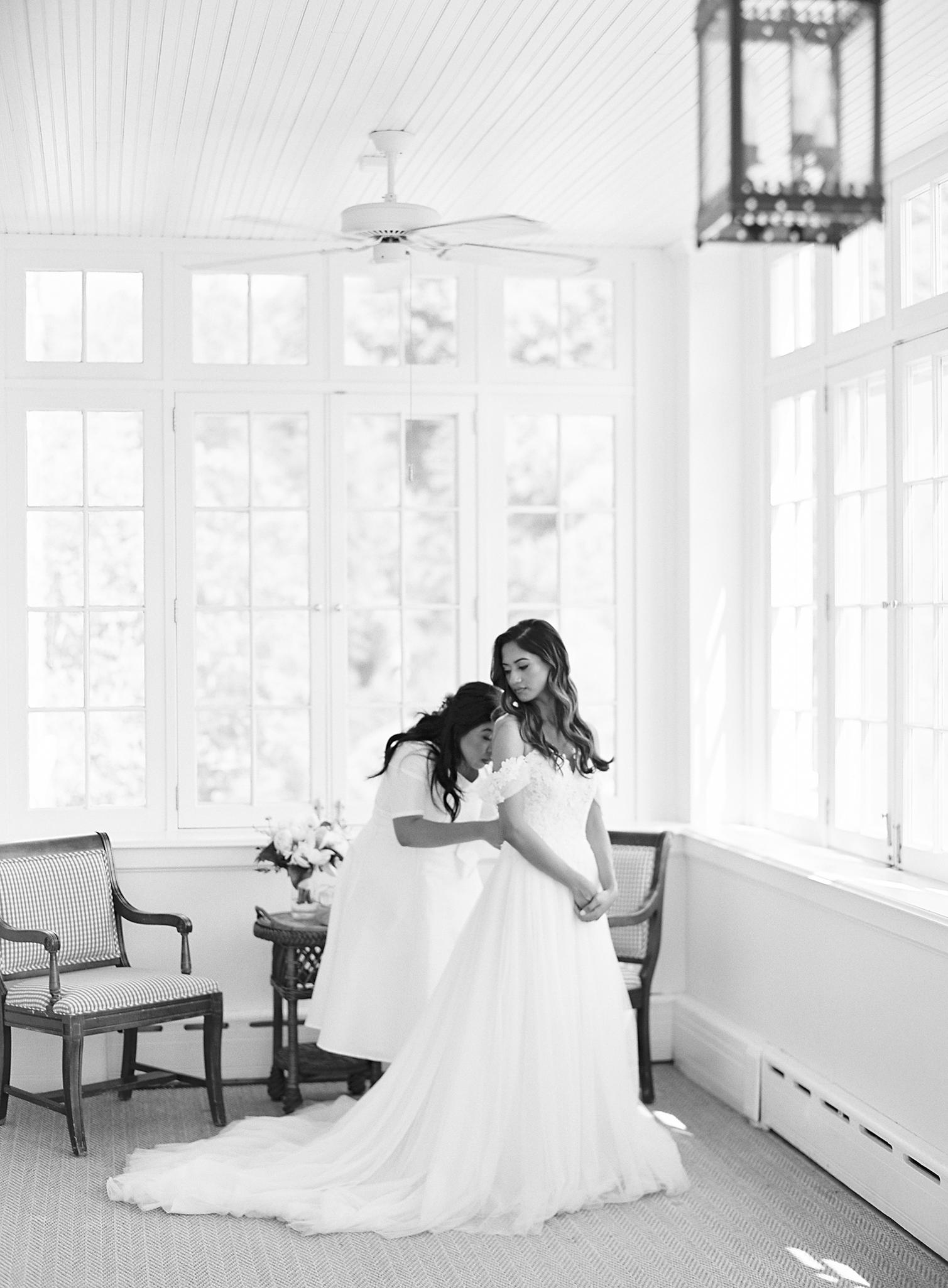 Bride getting buttoned up into here dress by sister for here Omni Homestead Resort Wedding.