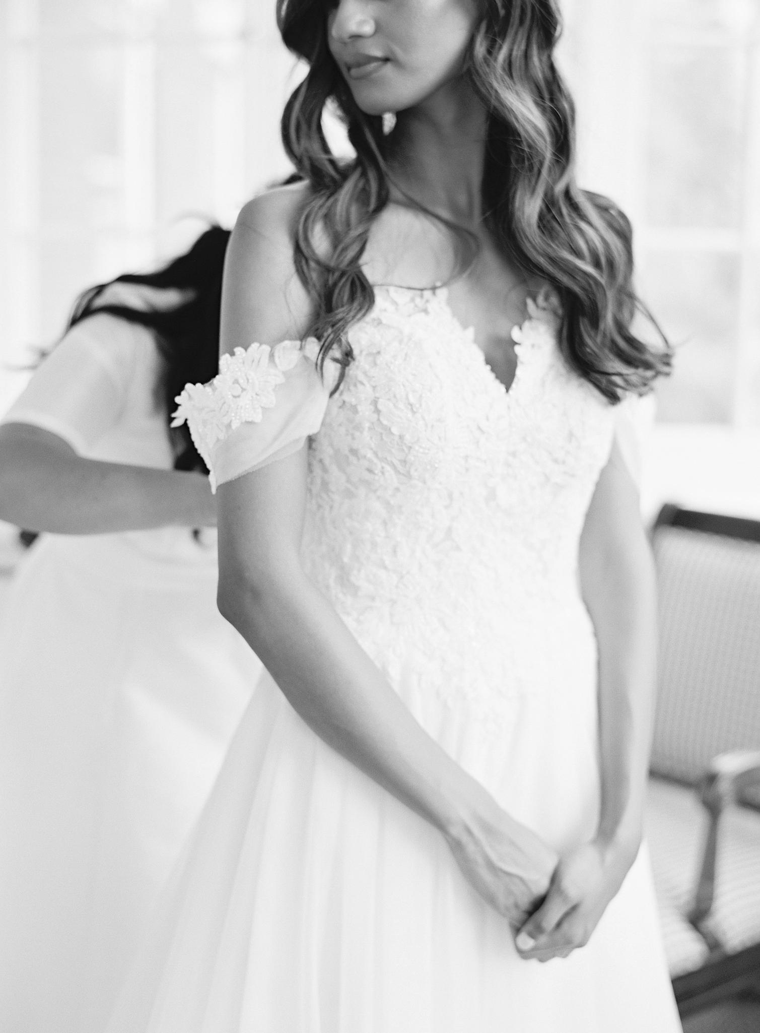 Bride getting buttoned up into here dress by sister for here Omni Homestead Resort Wedding.