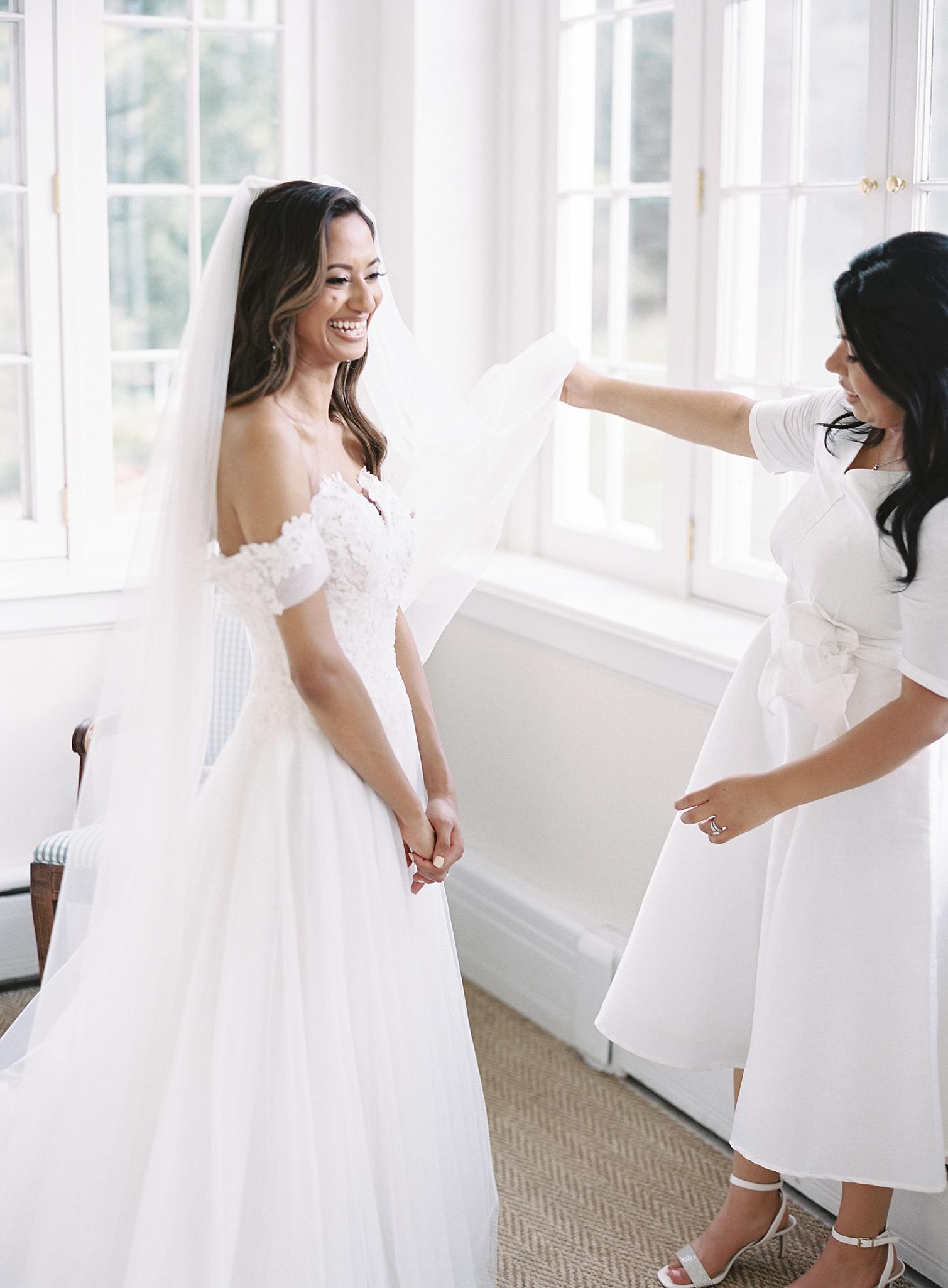 Bride and sister putting her veil on before her Omni Homestead Resort wedding.