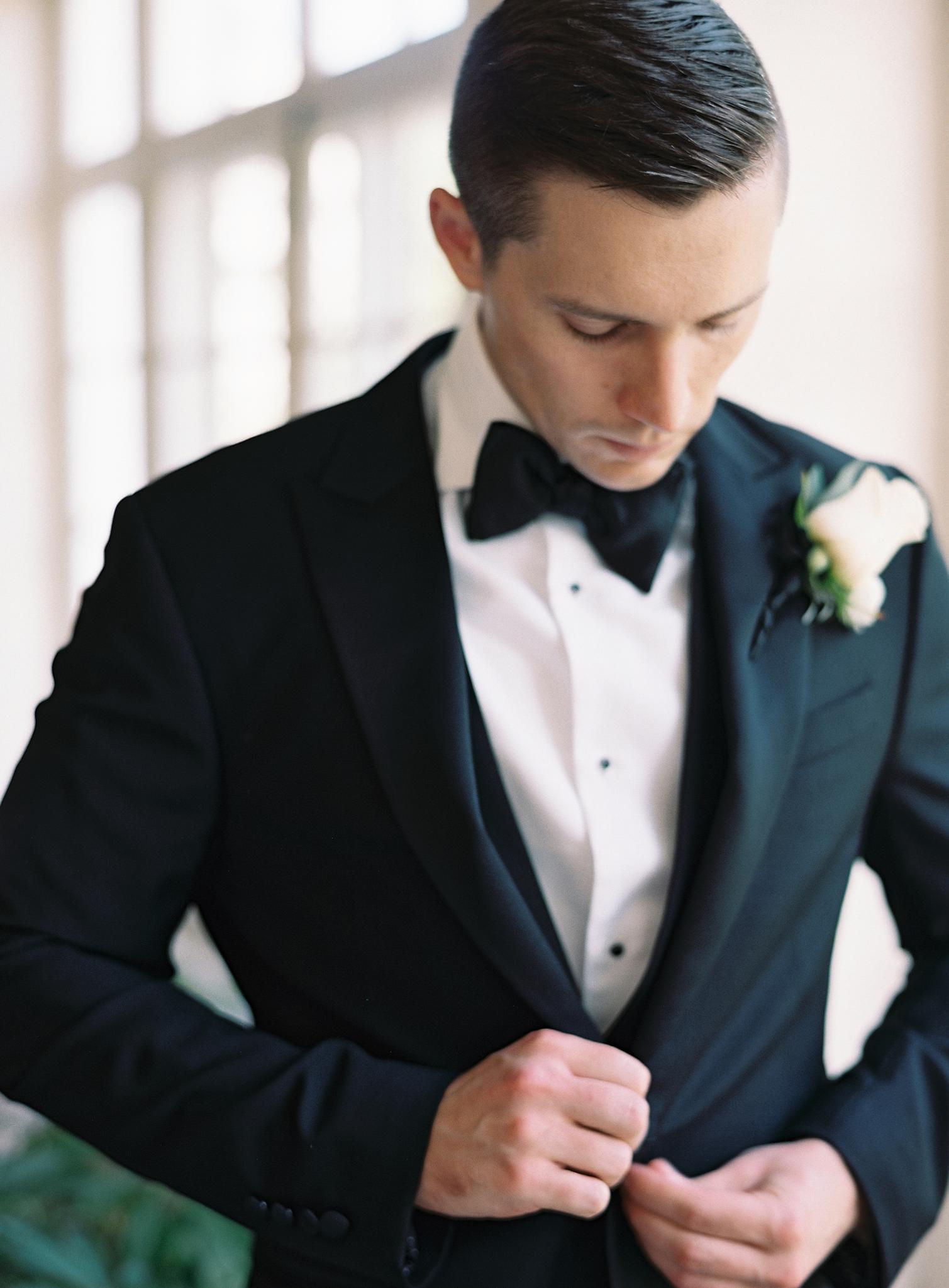 Groom buttoning his tuxedo before heading to his Omni Homestead Resort wedding.