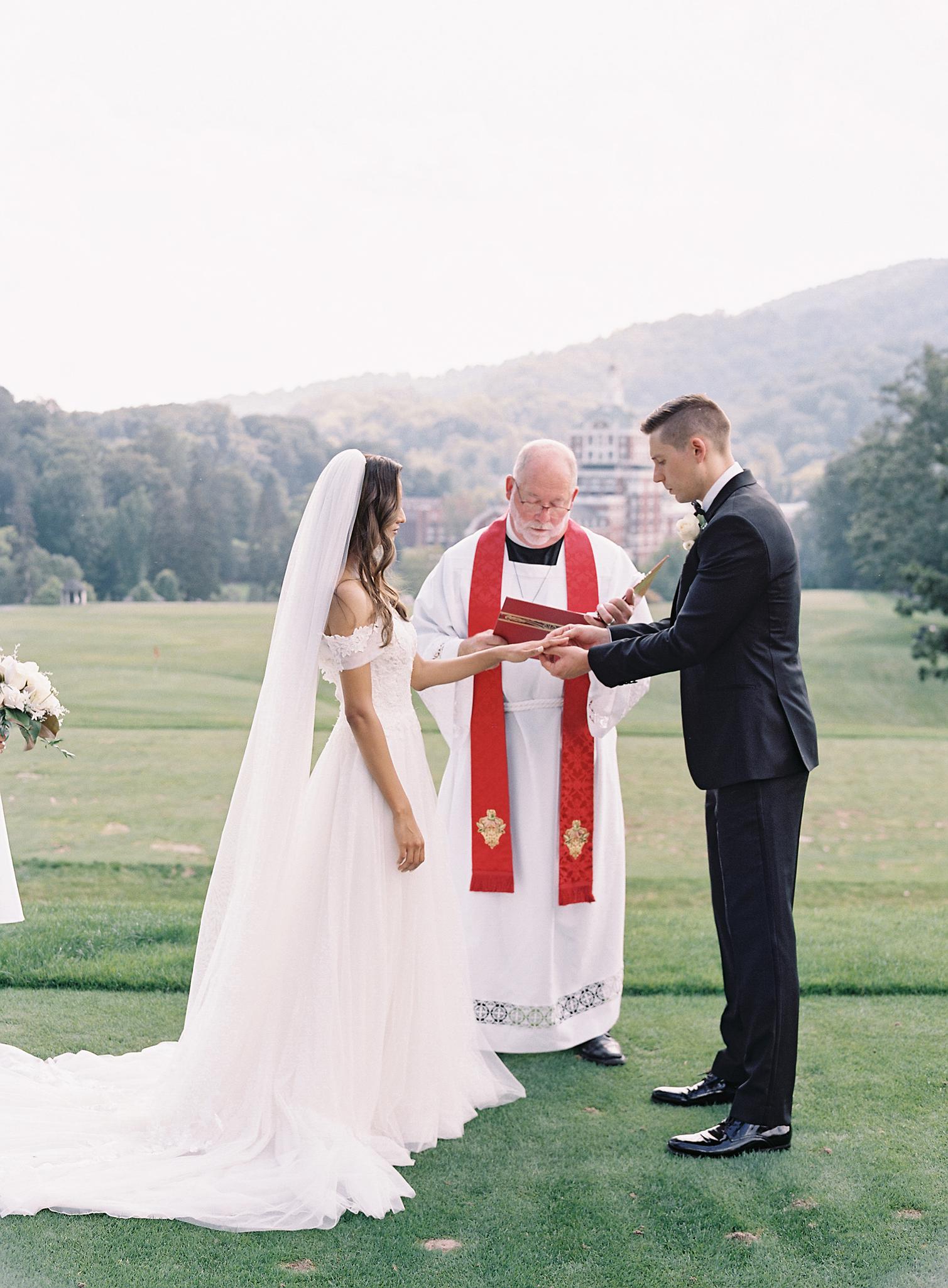 Bride and groom exchanging rings at their ceremony overlooking The Omni Homestead Resort.