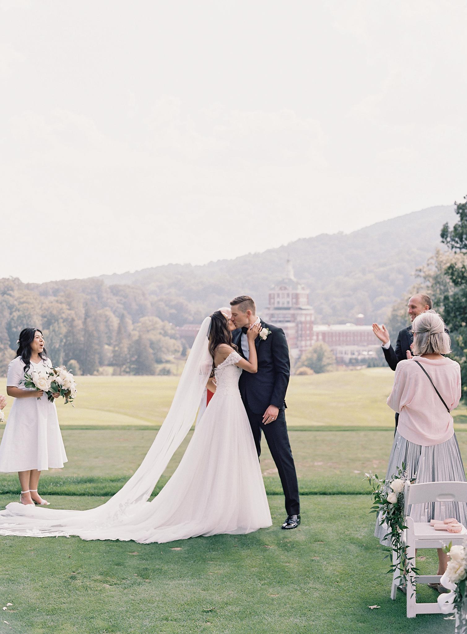 Bride and groom enjoying their first kiss at their ceremony overlooking The Omni Homestead Resort.