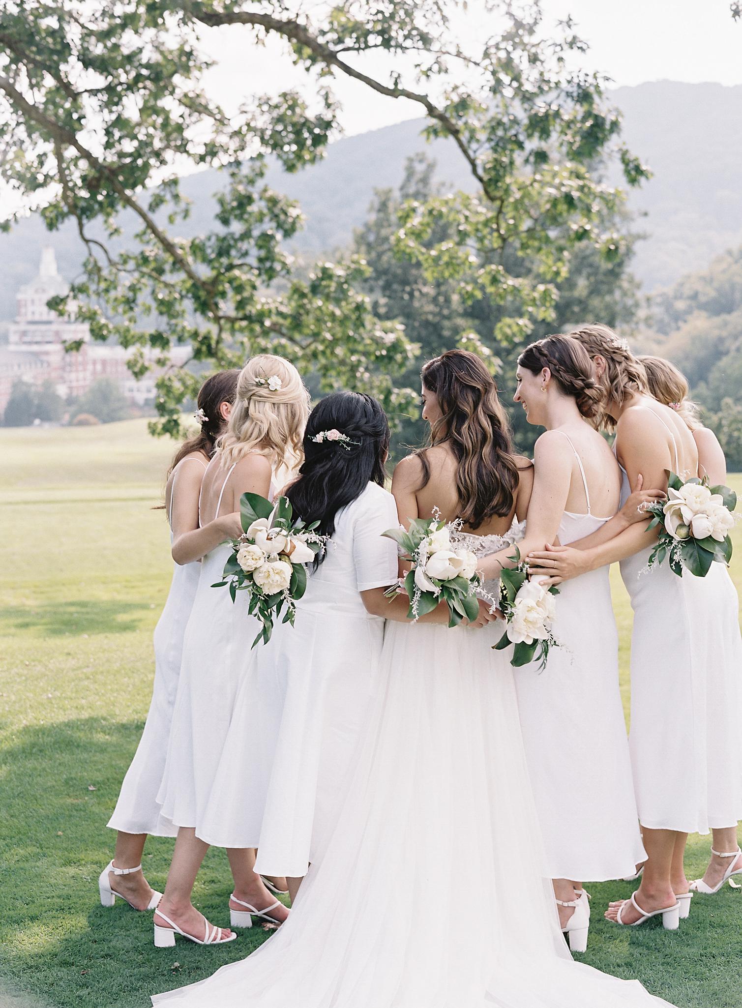 Bride and bridesmaids embracing after a wedding at The Omni Homestead Resort.