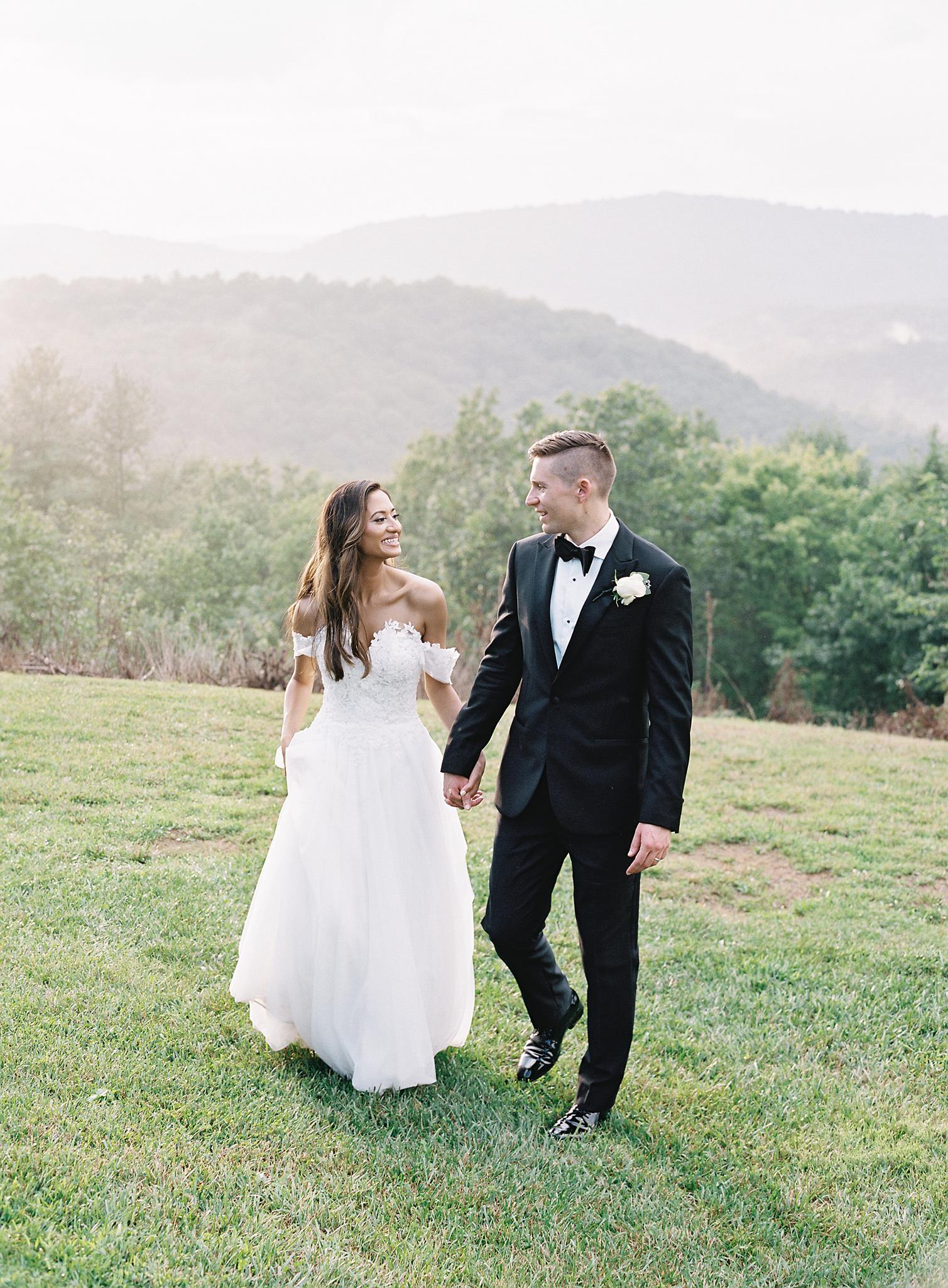 Bride and groom walking through the meadow overlooking the blue ridge mountains at their Omni Homestead Resort wedding.