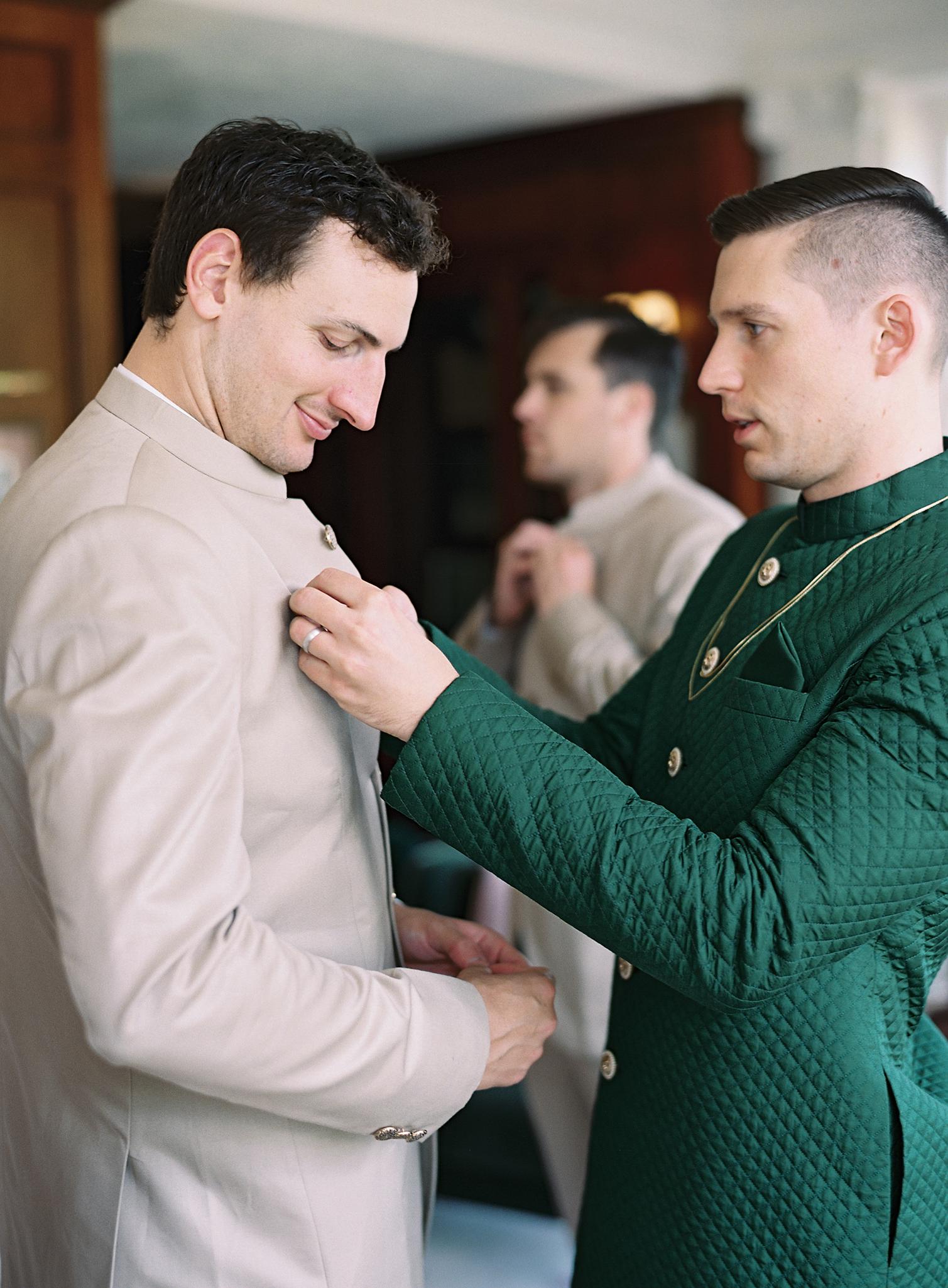 Groom helping pin his groom's sherwani before their wedding reception at The Omni Homestead Resort.