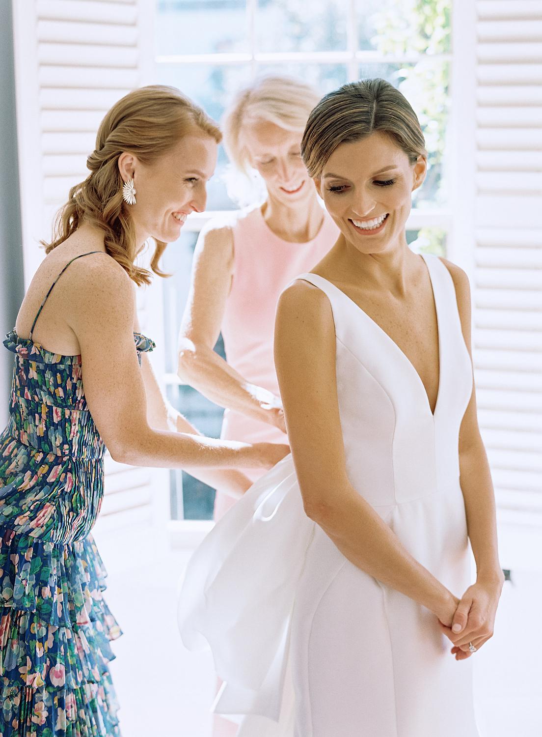 Bride getting zipped into her dress by mother and sister getting ready for her William Paca House Wedding in Annapolis