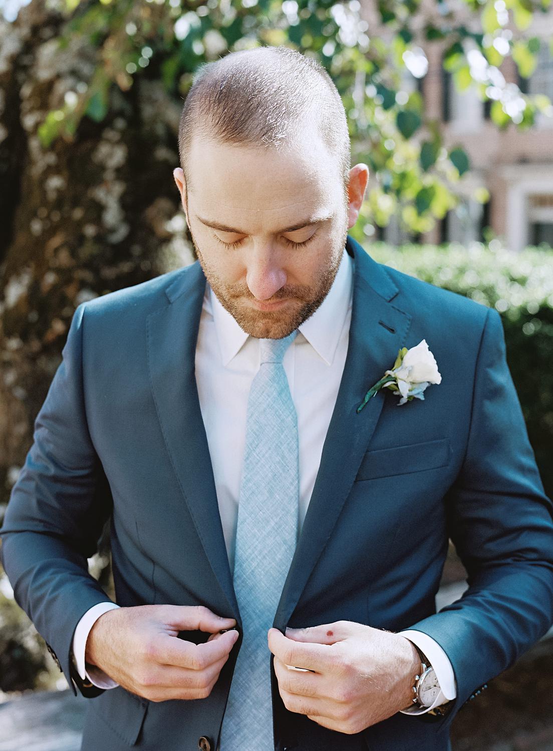 Groom buttoning his suit coat while waiting for his first look with his bride at their William Paca House wedding in Annapolis