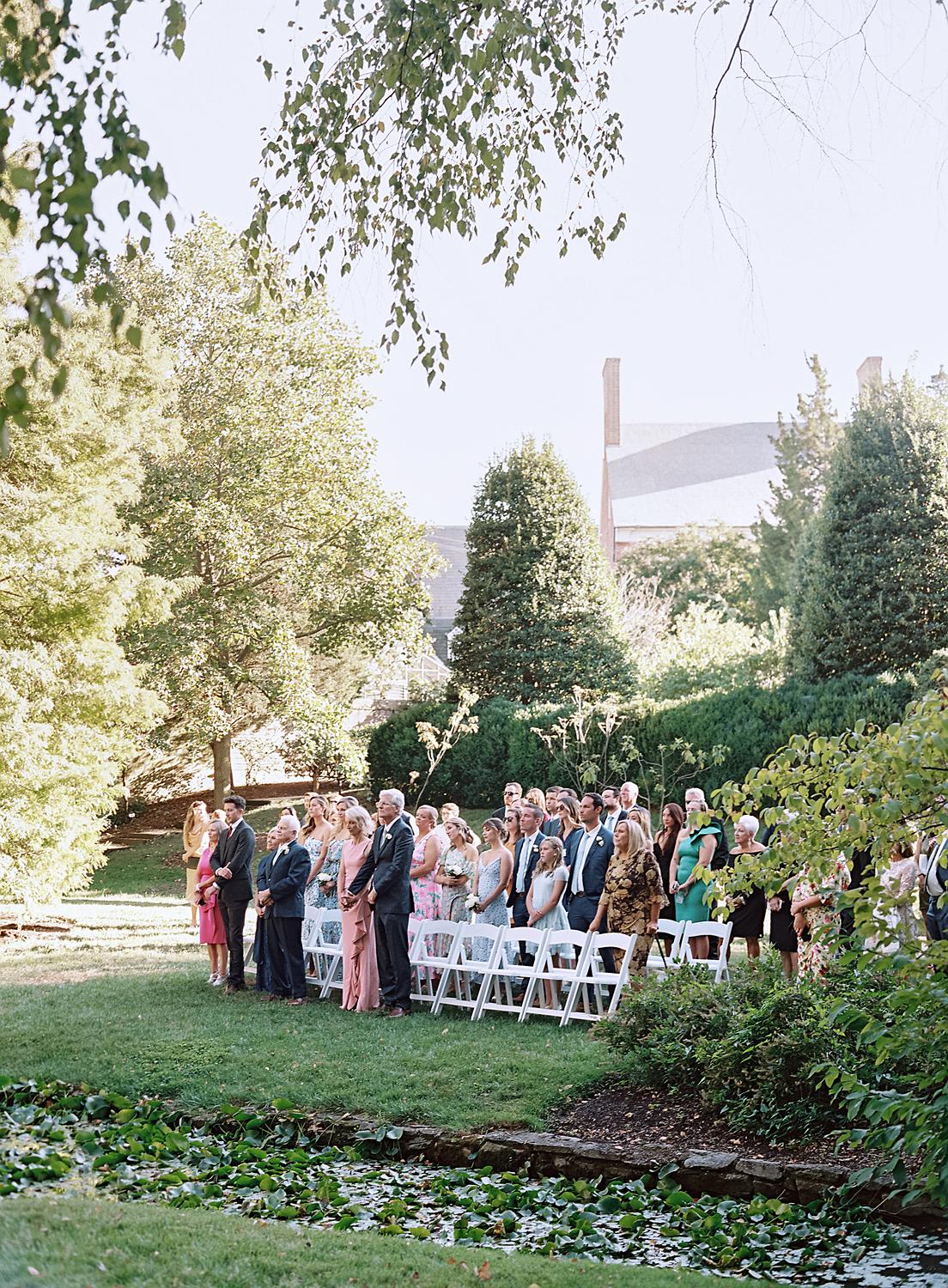 Family and guest looking on as the bride and groom say vows at their William Paca House wedding in Annapolis.