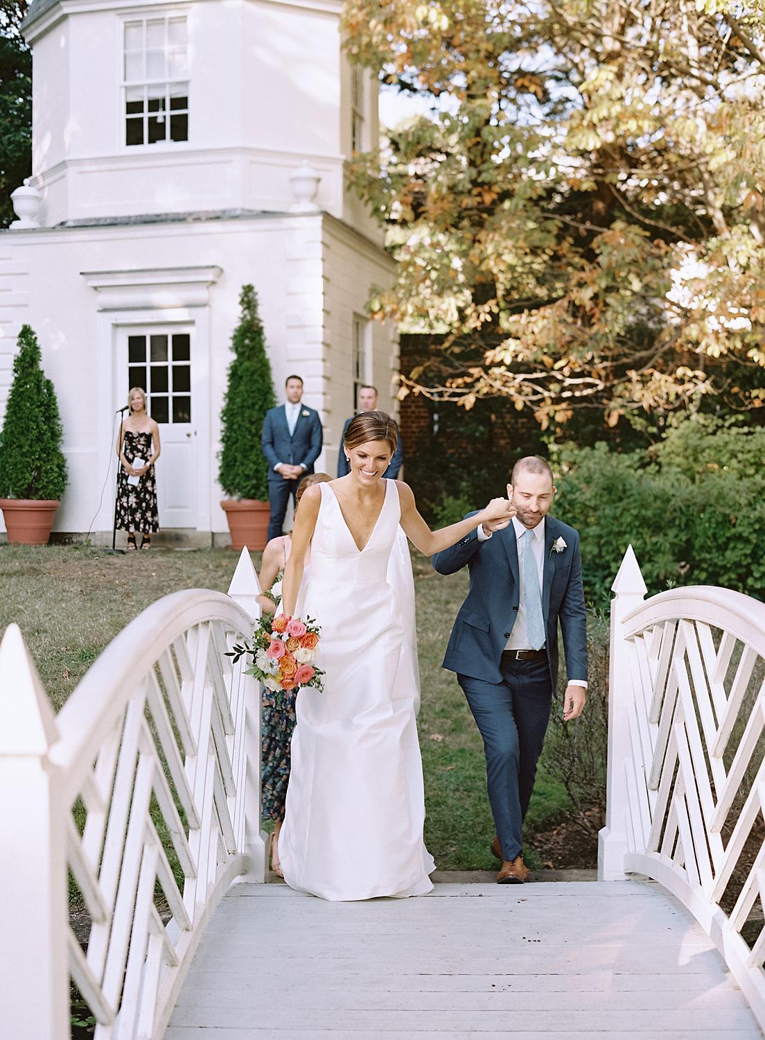 Bride and groom walking back across bridge after their ceremony at the William Paca House