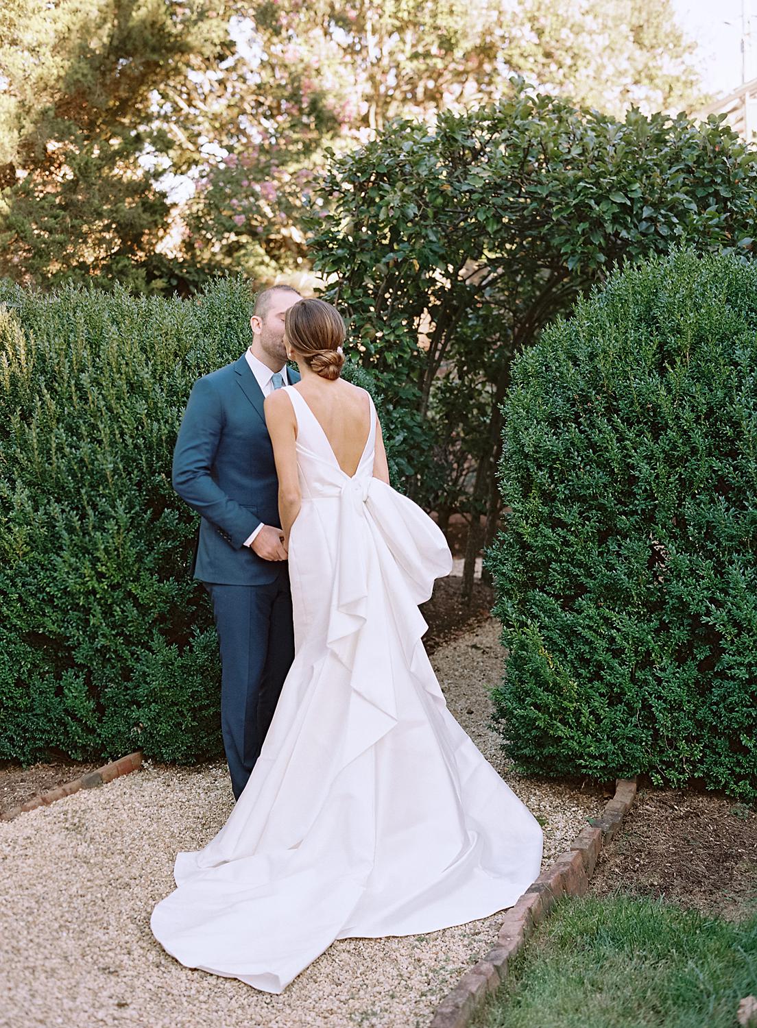 Bride kissing groom among the gardens of The William Paca House at their wedding.